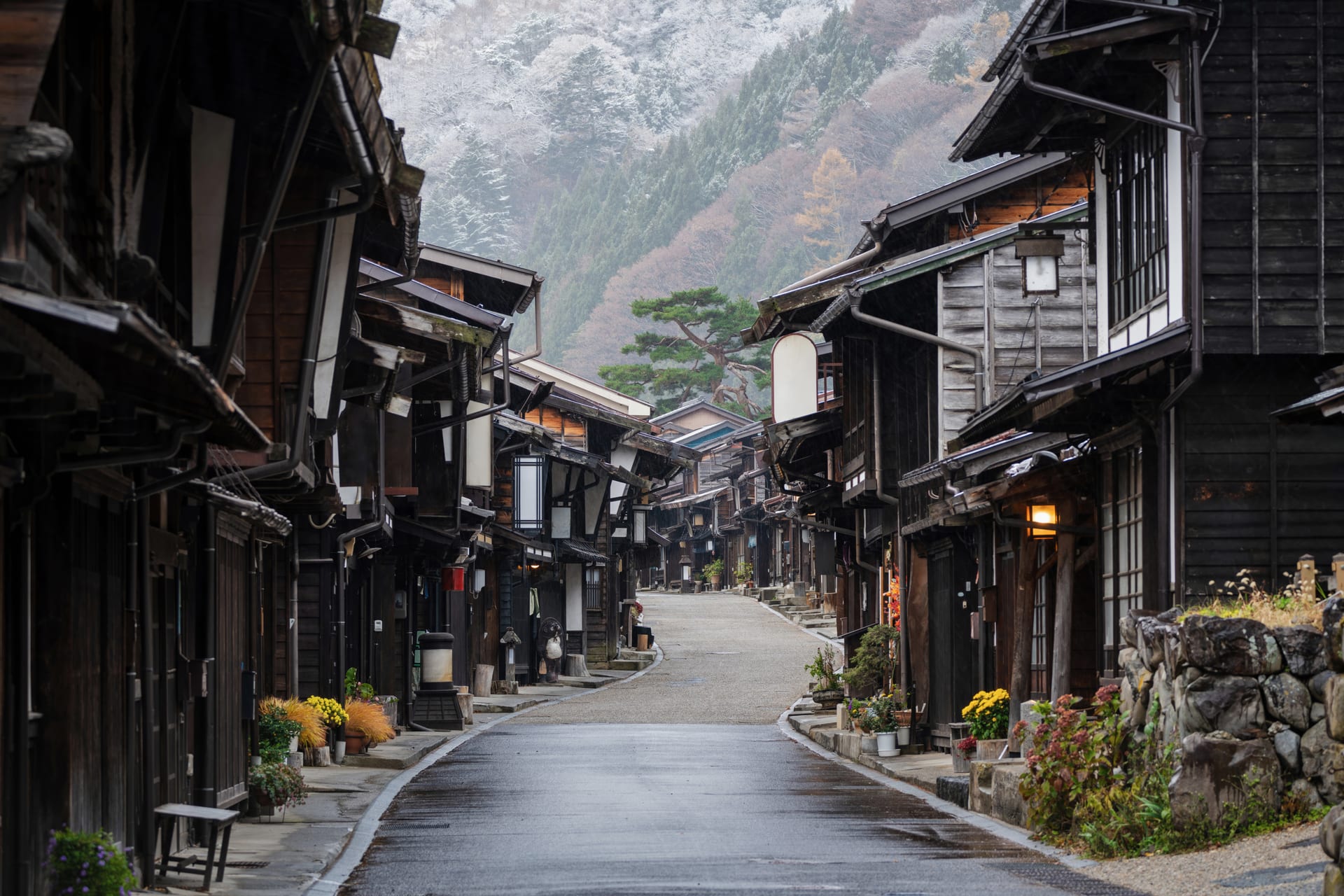 An empty street of dark timber inns leading towards snow-dusted hills