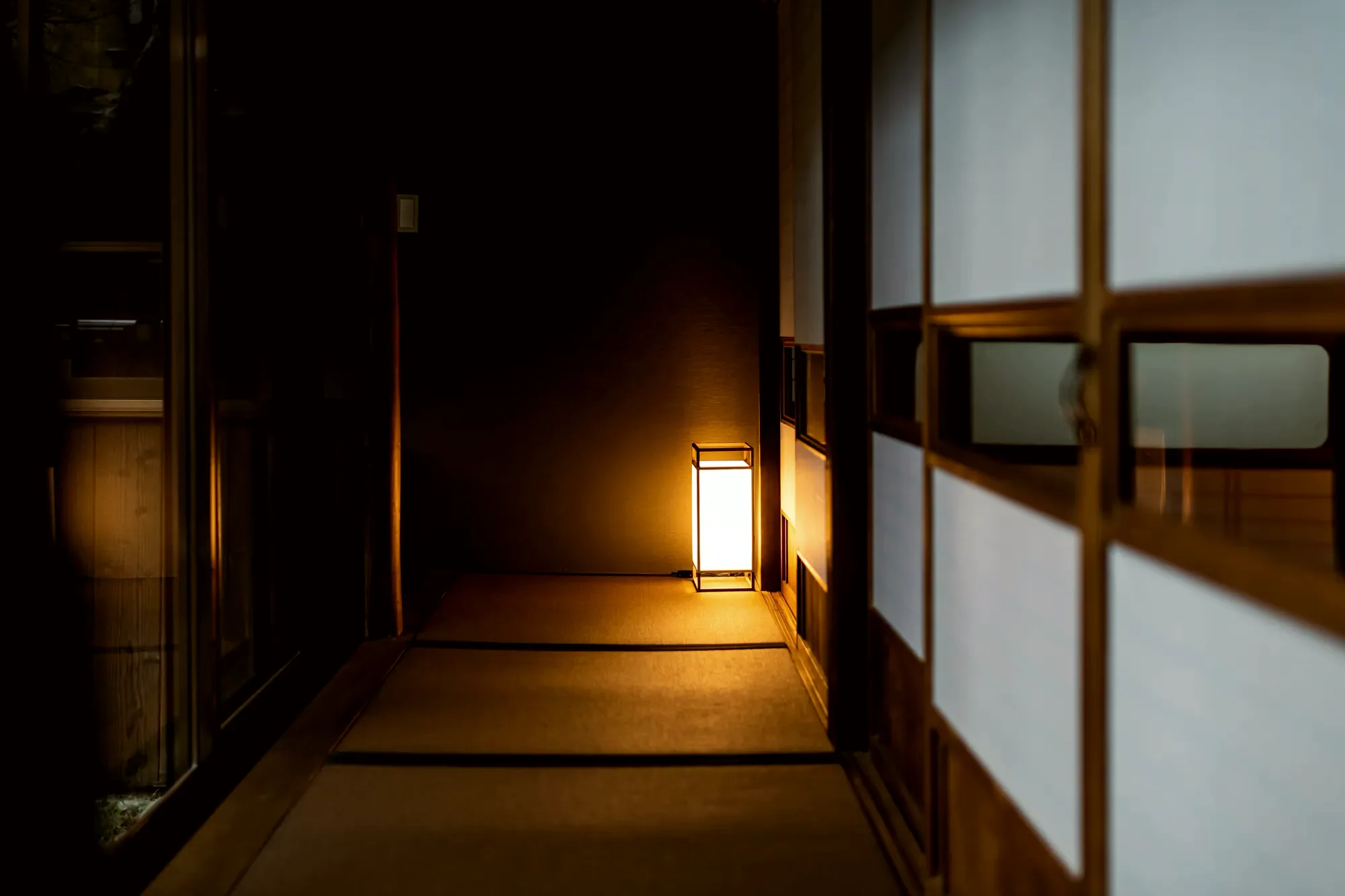 A lantern lit in the corridor of a Kyoto house at dusk