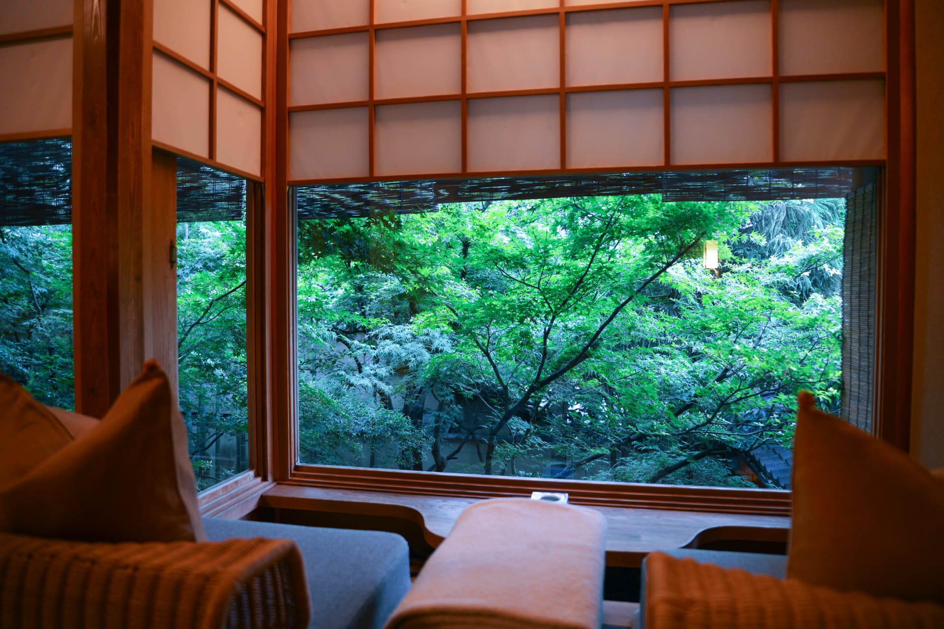 A cushioned window seat in a tatami room of a ryokan, looking out through low windows