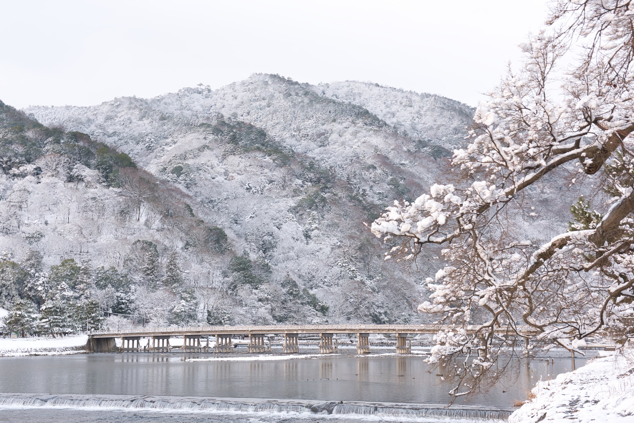 The long wooden Togetsukyo bridge beneath snow-covered mountains, Arashiyama, Kyoto