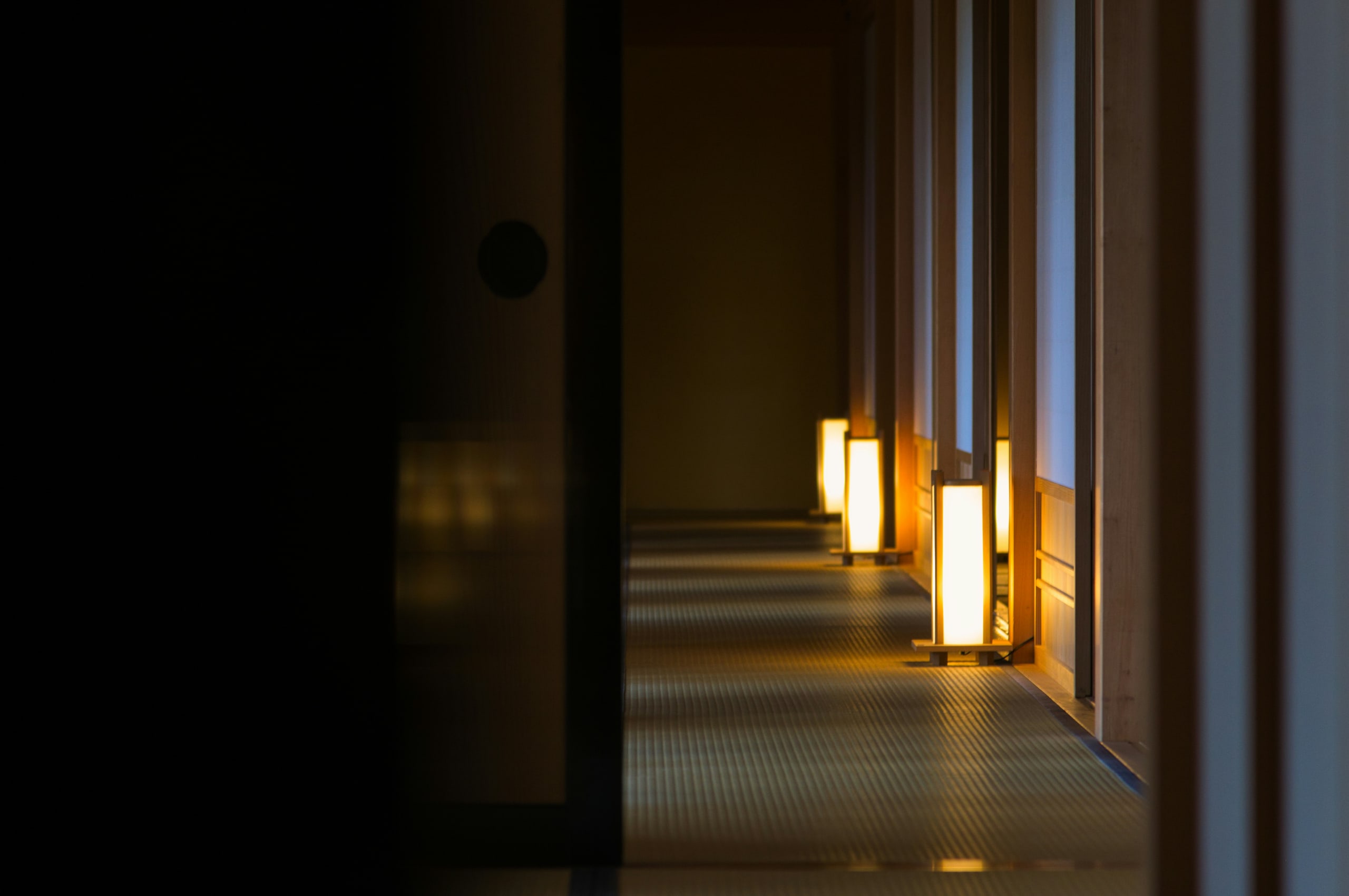A tatami corridor lit by paper lanterns at blue hour, Hakodate