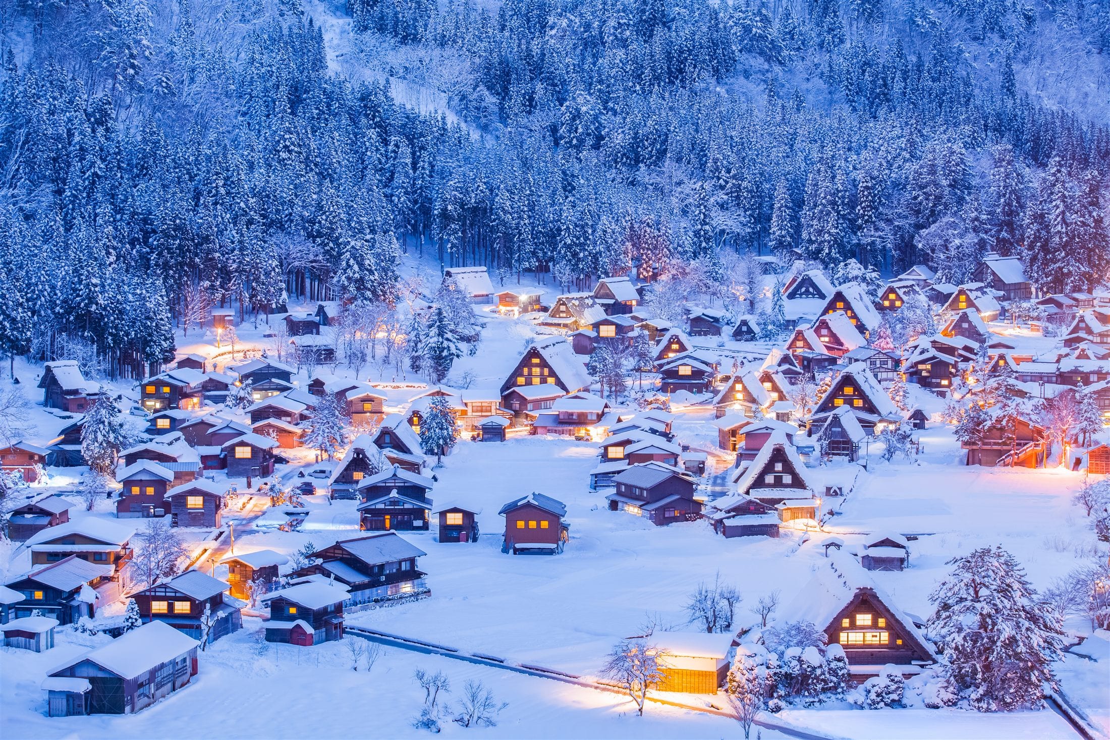 Farmhouse roofs lit at dusk under deep snow