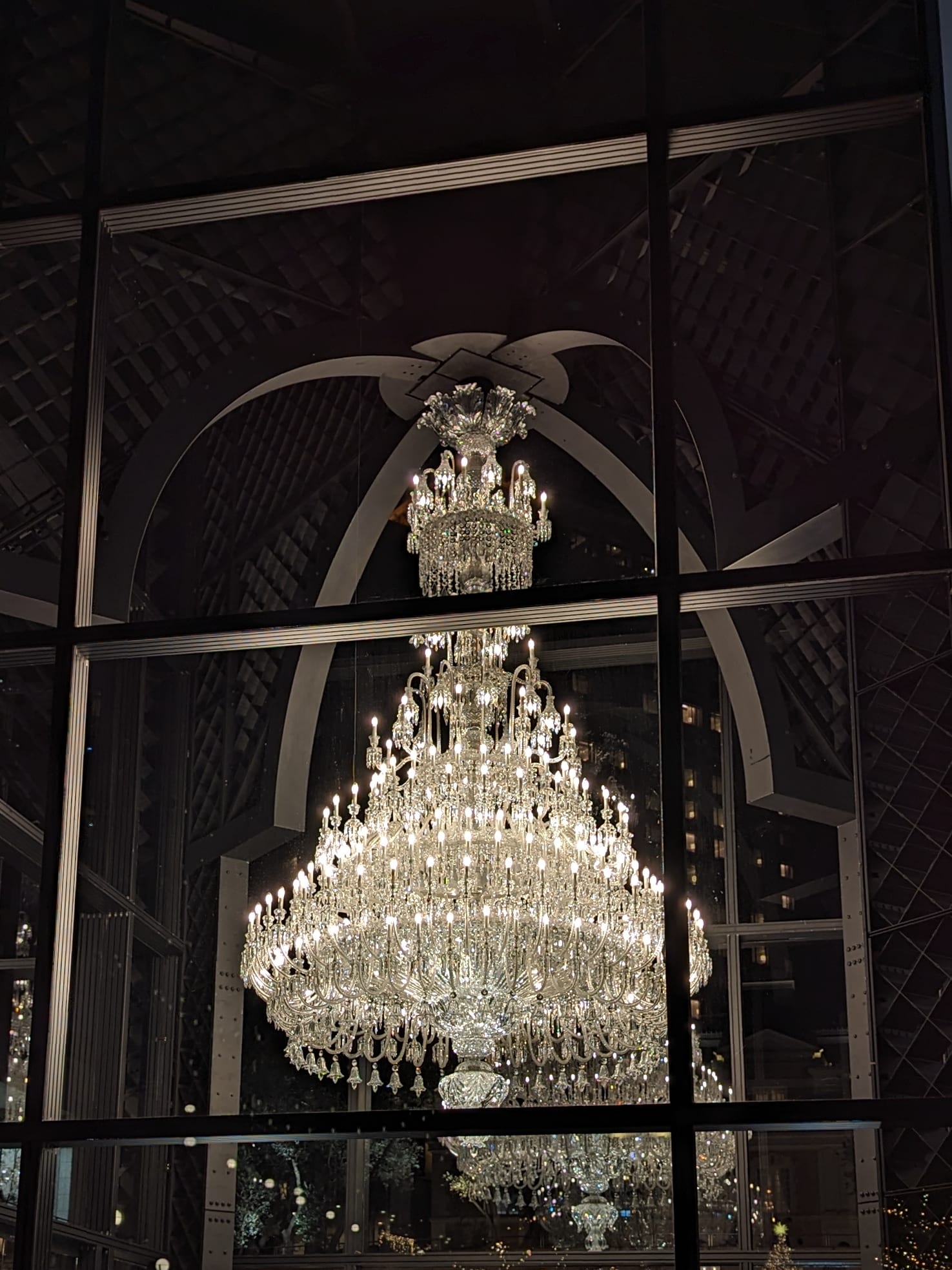 A tiered Baccarat crystal chandelier lit inside a tall glass pavilion at night, Yebisu Garden Place, Ebisu, Tokyo, at Christmas