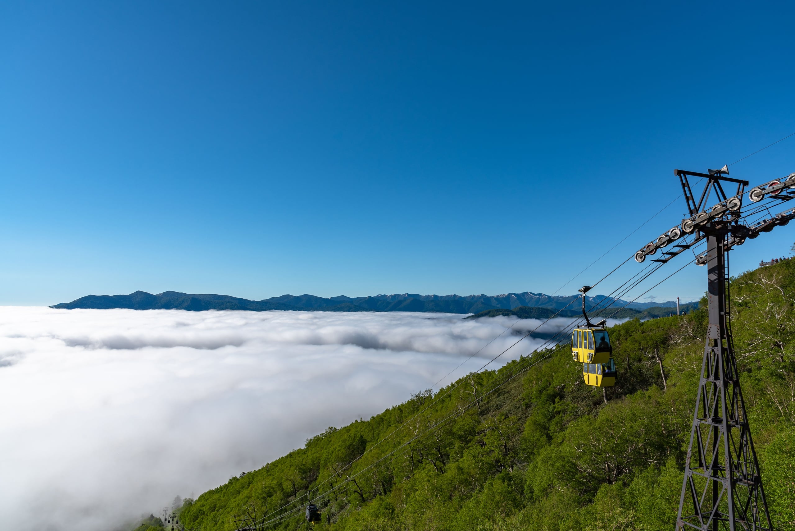 A yellow gondola climbing above a sea of cloud at the Unkai Terrace, Tomamu, Hokkaido