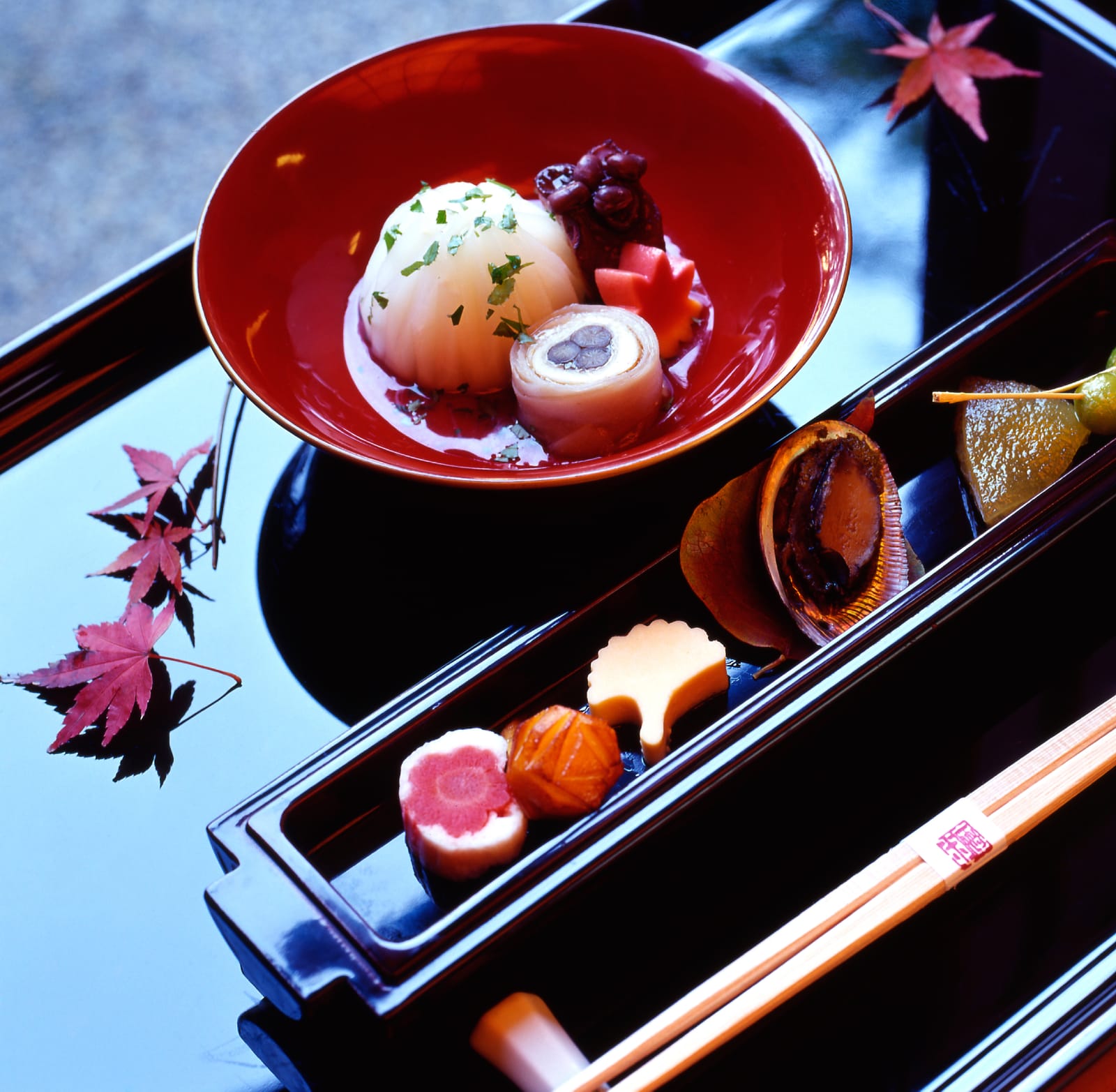 A small autumn kaiseki course on a lacquer tray with a maple-leaf garnish and abalone shell