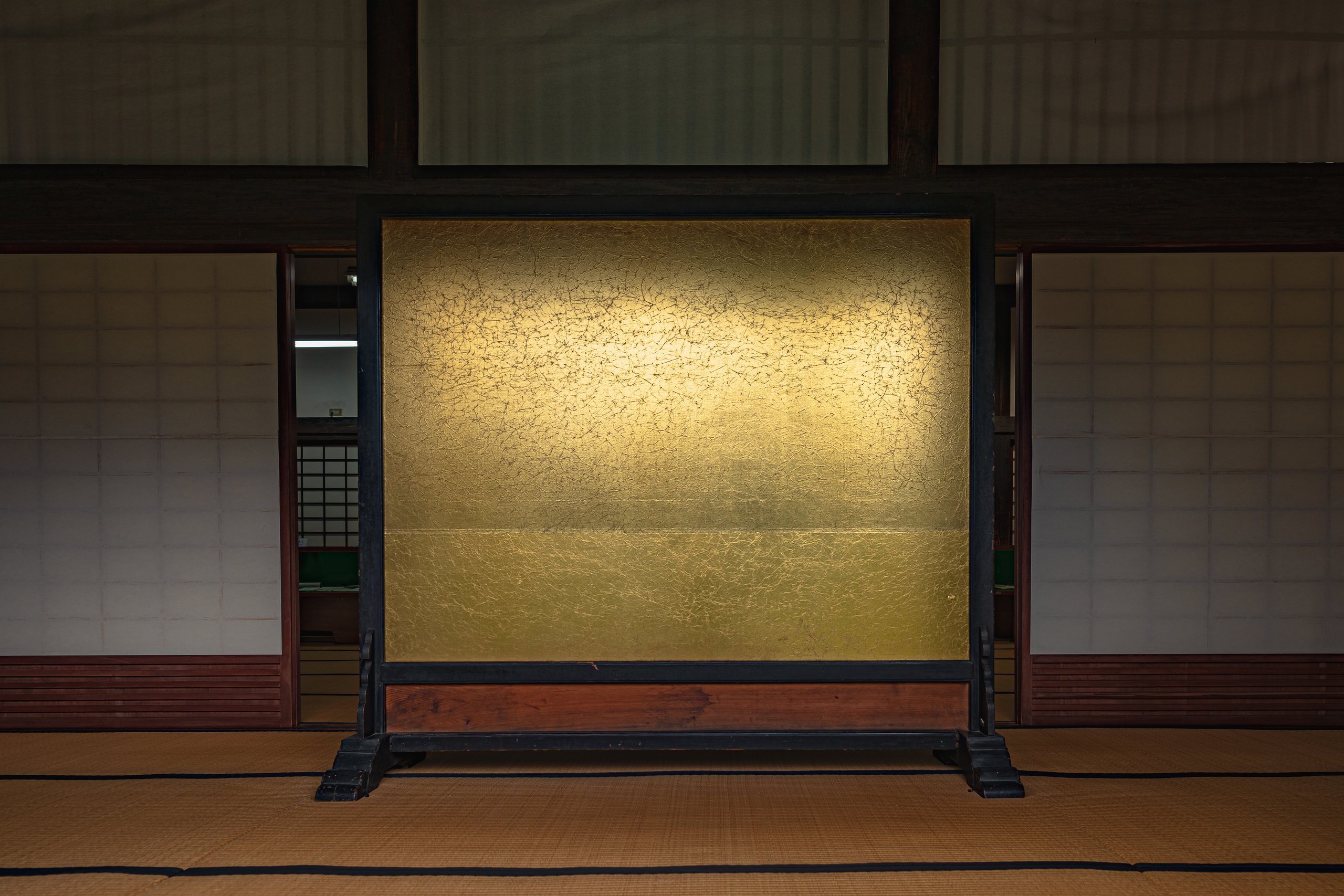 A single gold leaf folding screen stands in a tatami room