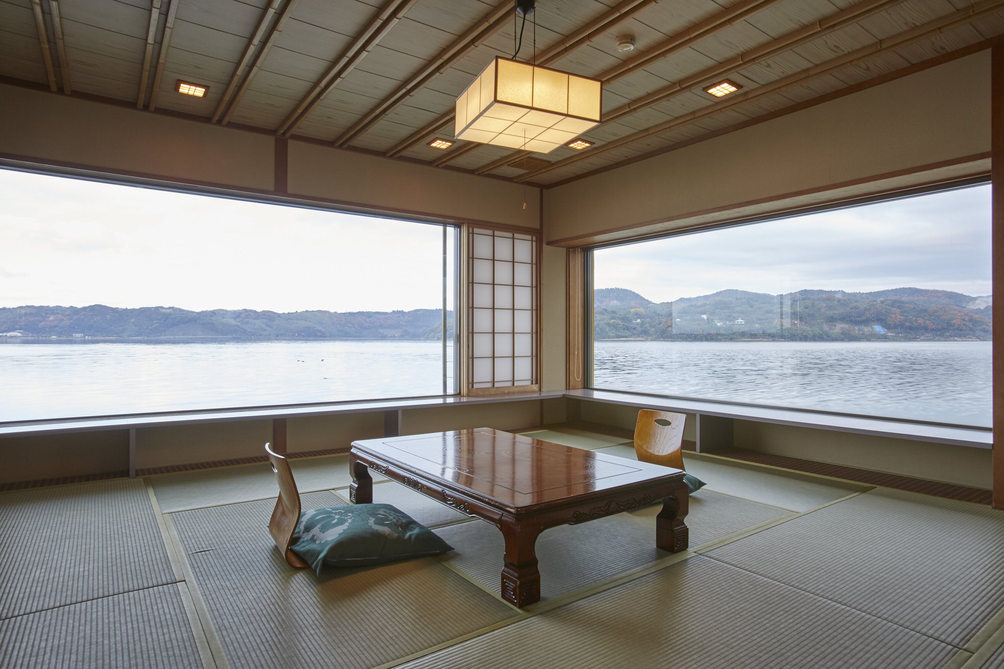 A corner tatami room with wide windows over a calm bay