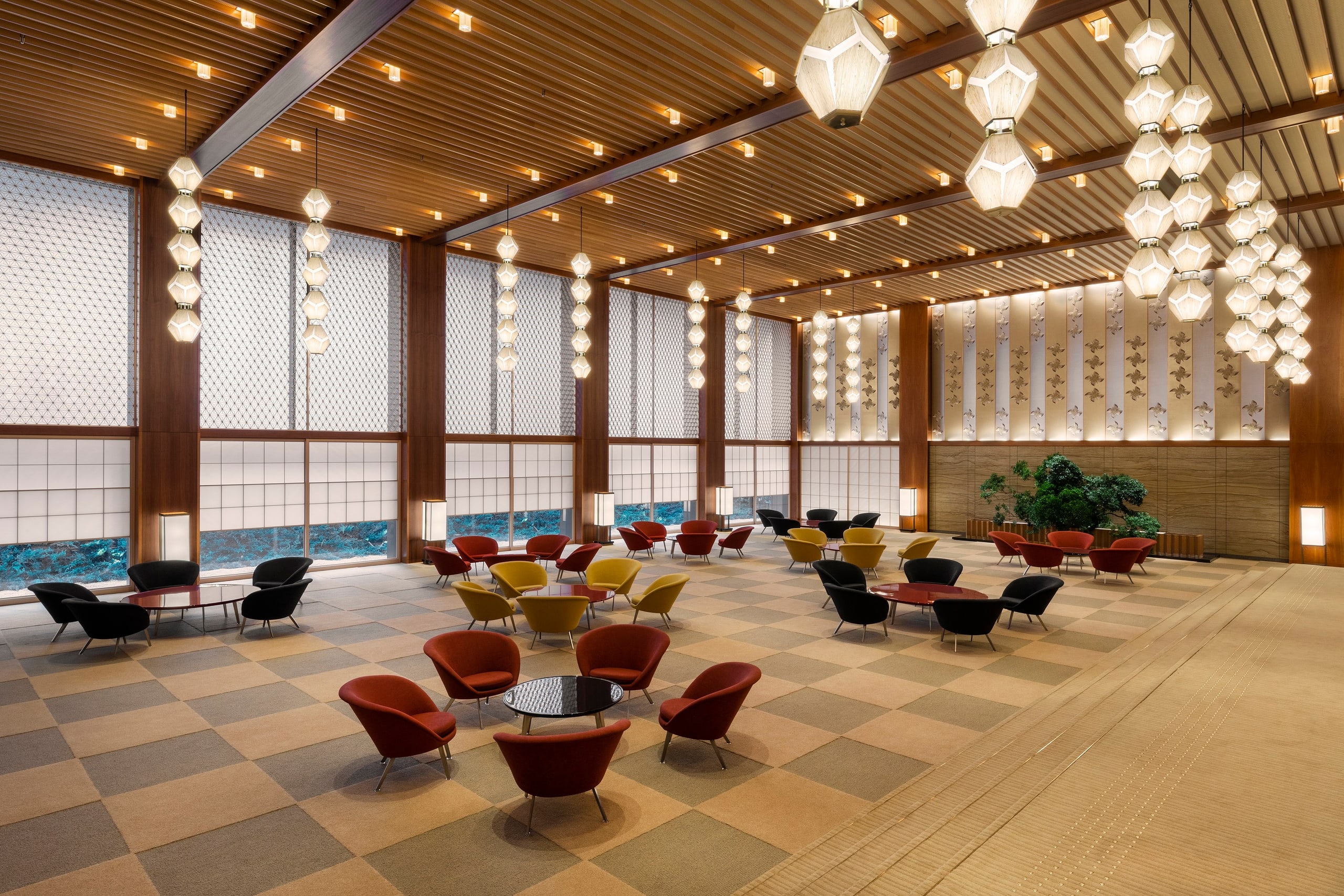 The long main lobby of The Okura Tokyo, low red and gold chairs on a chequered floor beneath strings of hexagonal paper lanterns