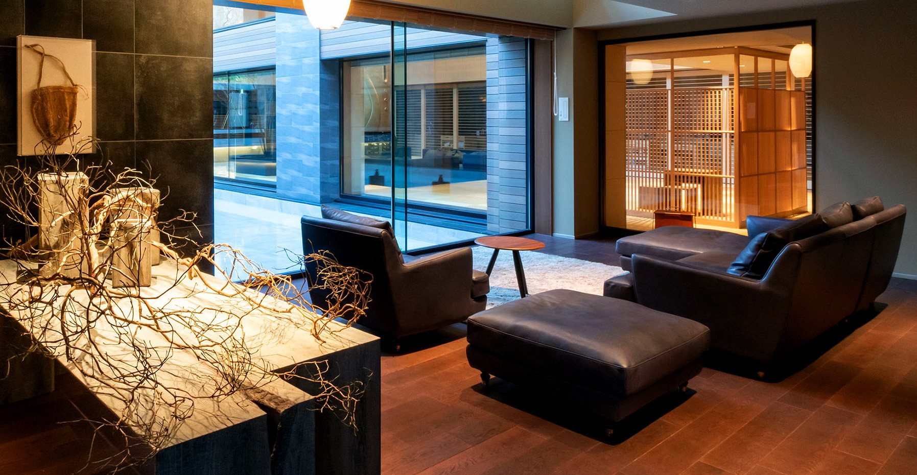 Leather armchairs and a sculpture of white branches in the dark-toned lounge of Ao no Za
