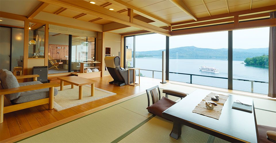 A guest room at Hinanoza, tatami and a low table before a wall of windows onto Lake Akan