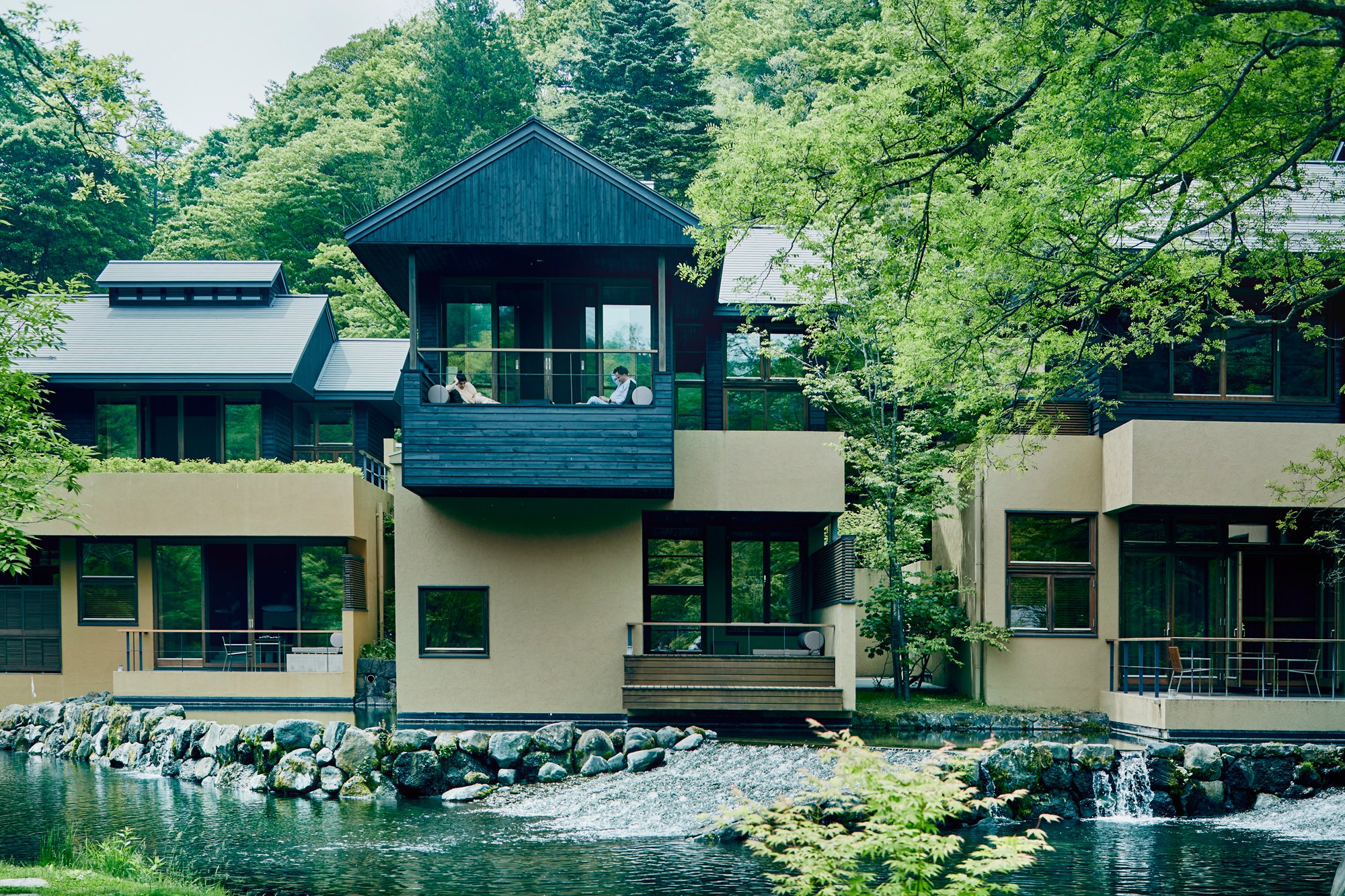 The pavilions above a stream and a low weir among green trees