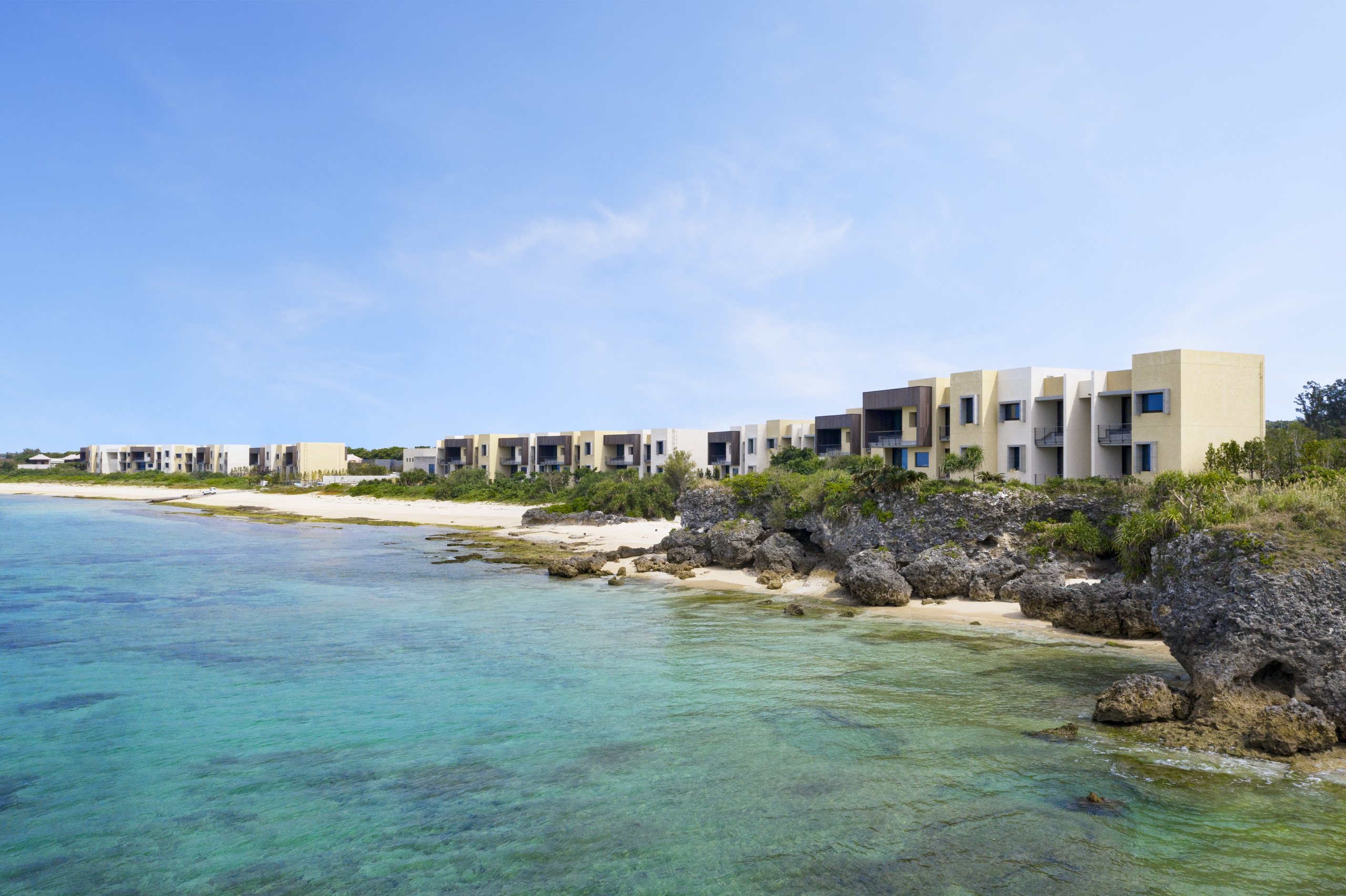 The resort's low buildings along a rocky shore of clear blue water