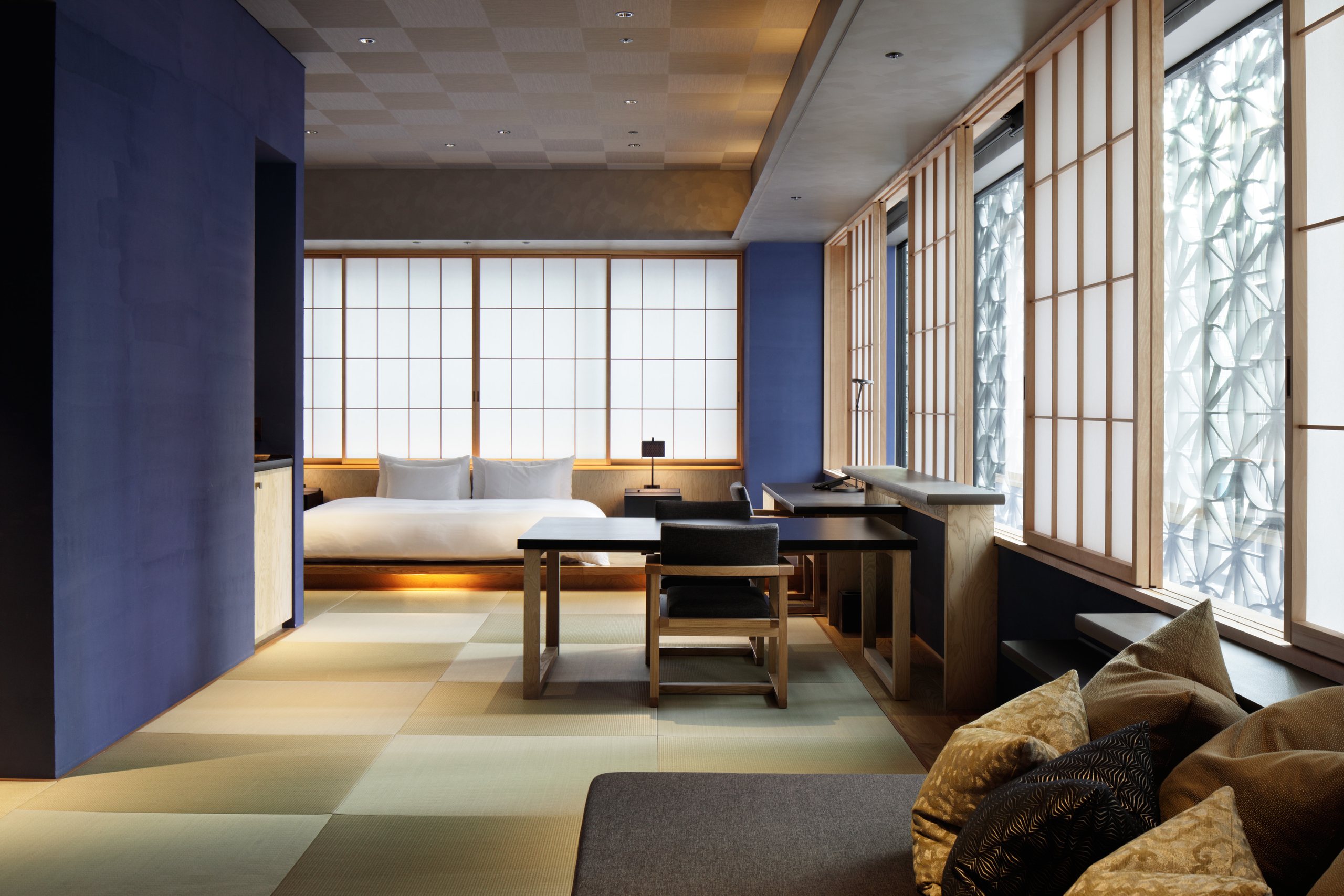A tatami room with a low bed, a writing desk and a window of shoji screens