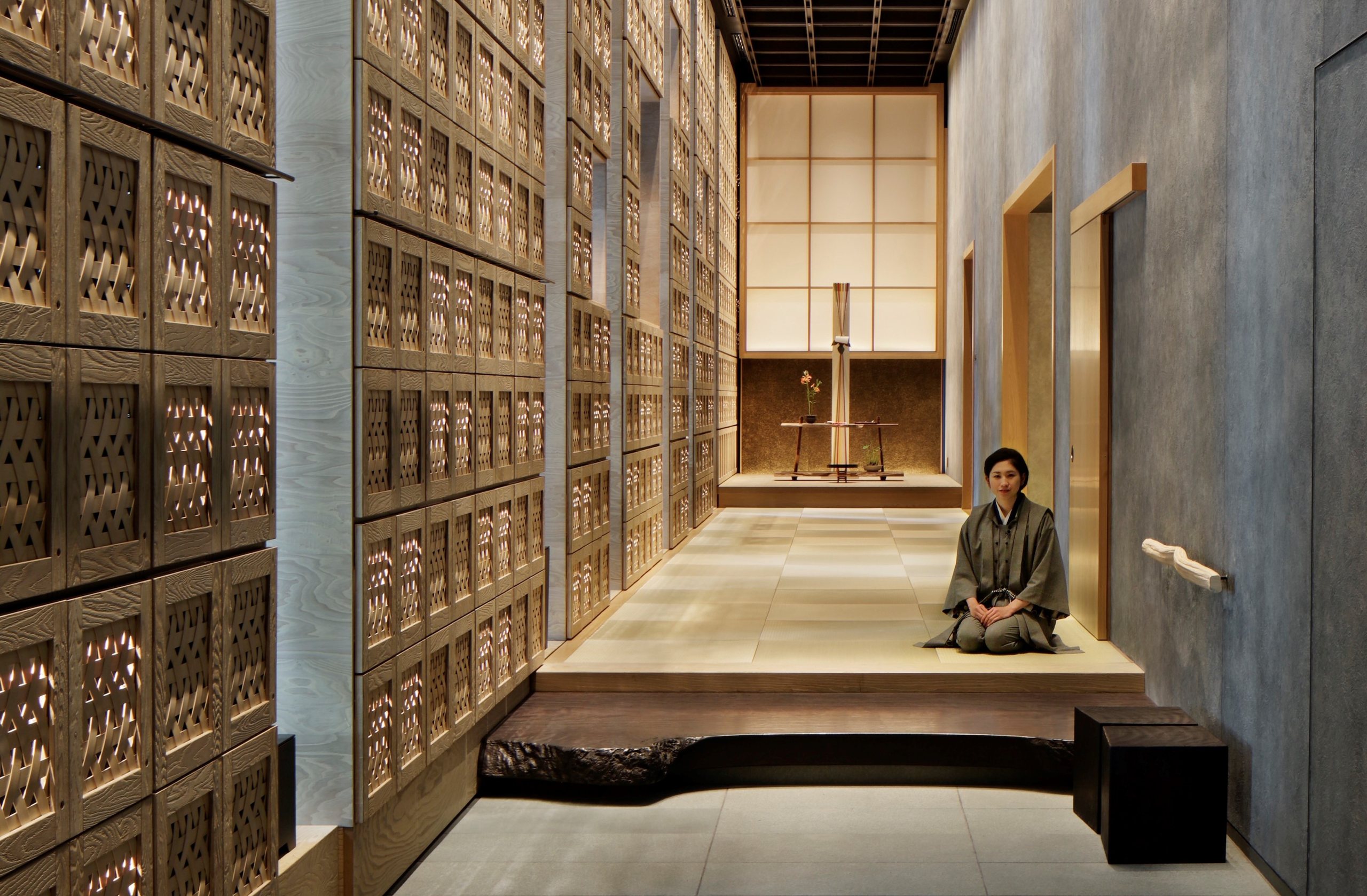 A long entrance hall lined with lattice cabinets, a member of staff kneeling on the step