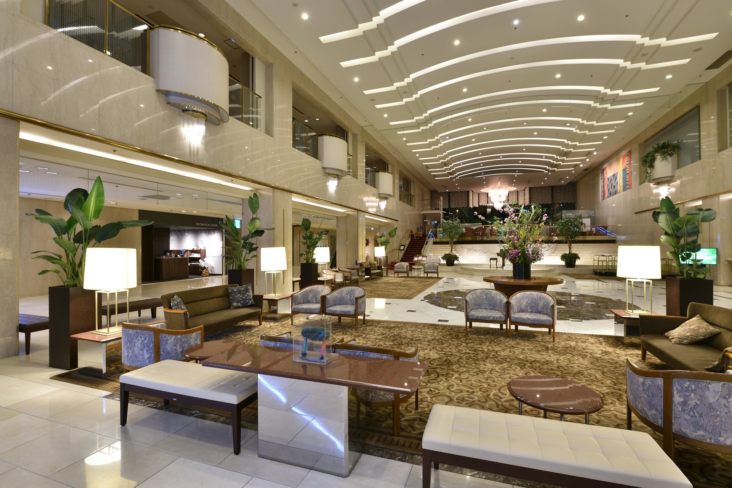 The long lobby lounge of Hotel Granvia Hiroshima, armchairs and palms beneath a curved, lit ceiling