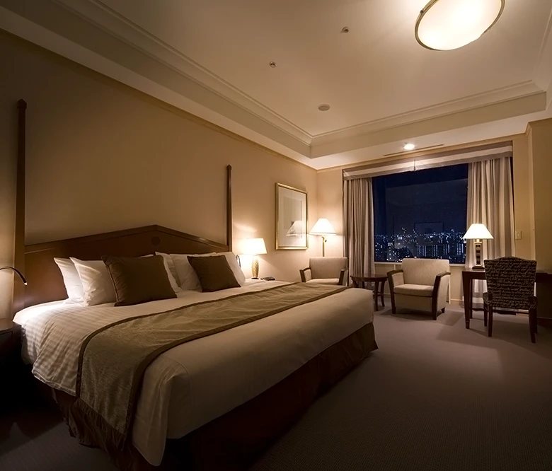 A deluxe room on the Imperial Floor, a wide bed and armchairs before a window onto the city at night