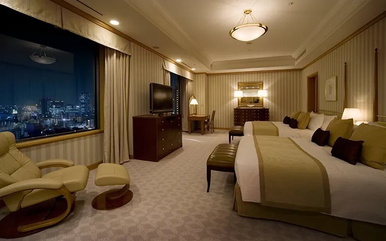 A suite bedroom at night, a reclining chair before a long window onto the city lights