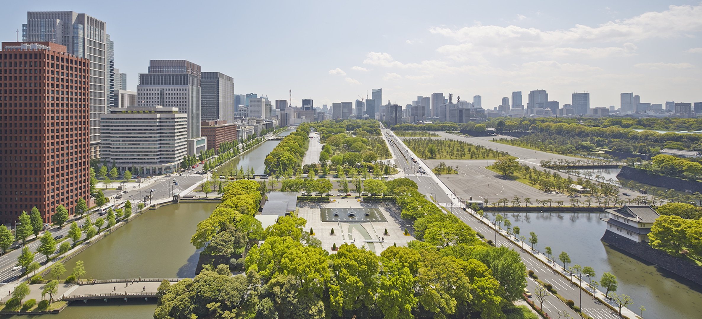 The gardens of the Imperial Palace and their moats seen from above, the towers of Tokyo behind