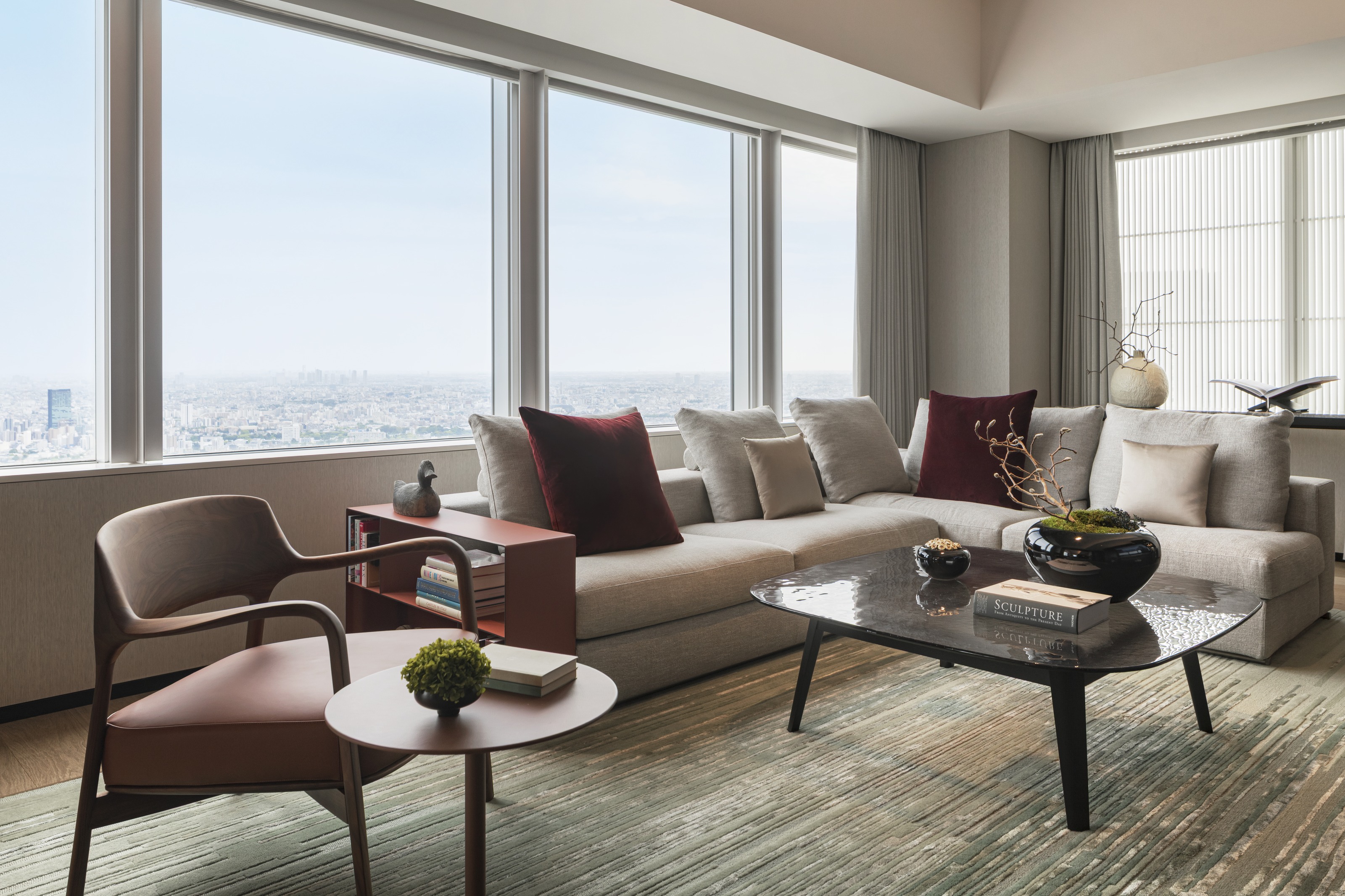 A suite living room with a deep sofa and tall windows over the city