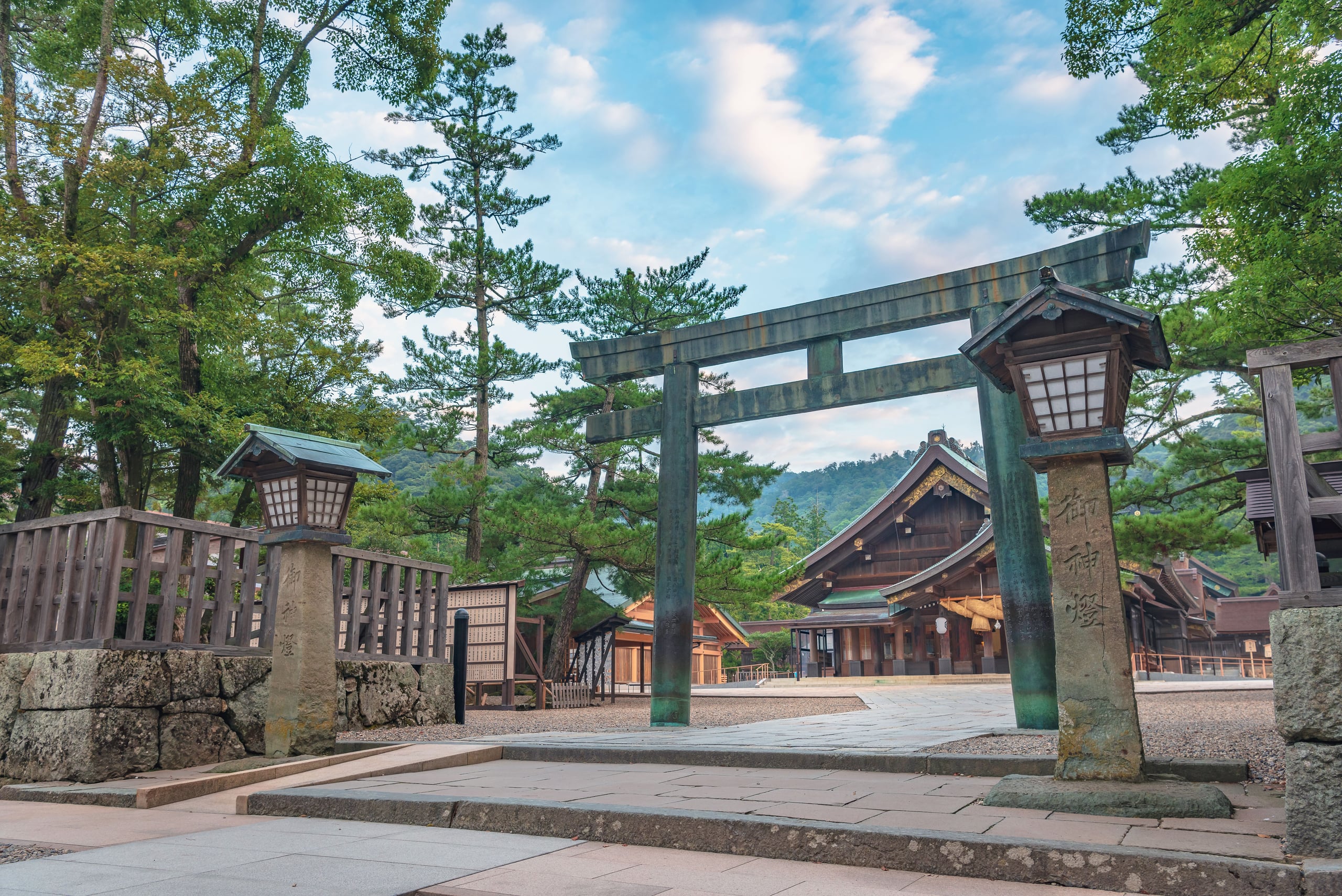 A weathered bronze torii beside a stone lantern at Izumo Taisha, Shimane