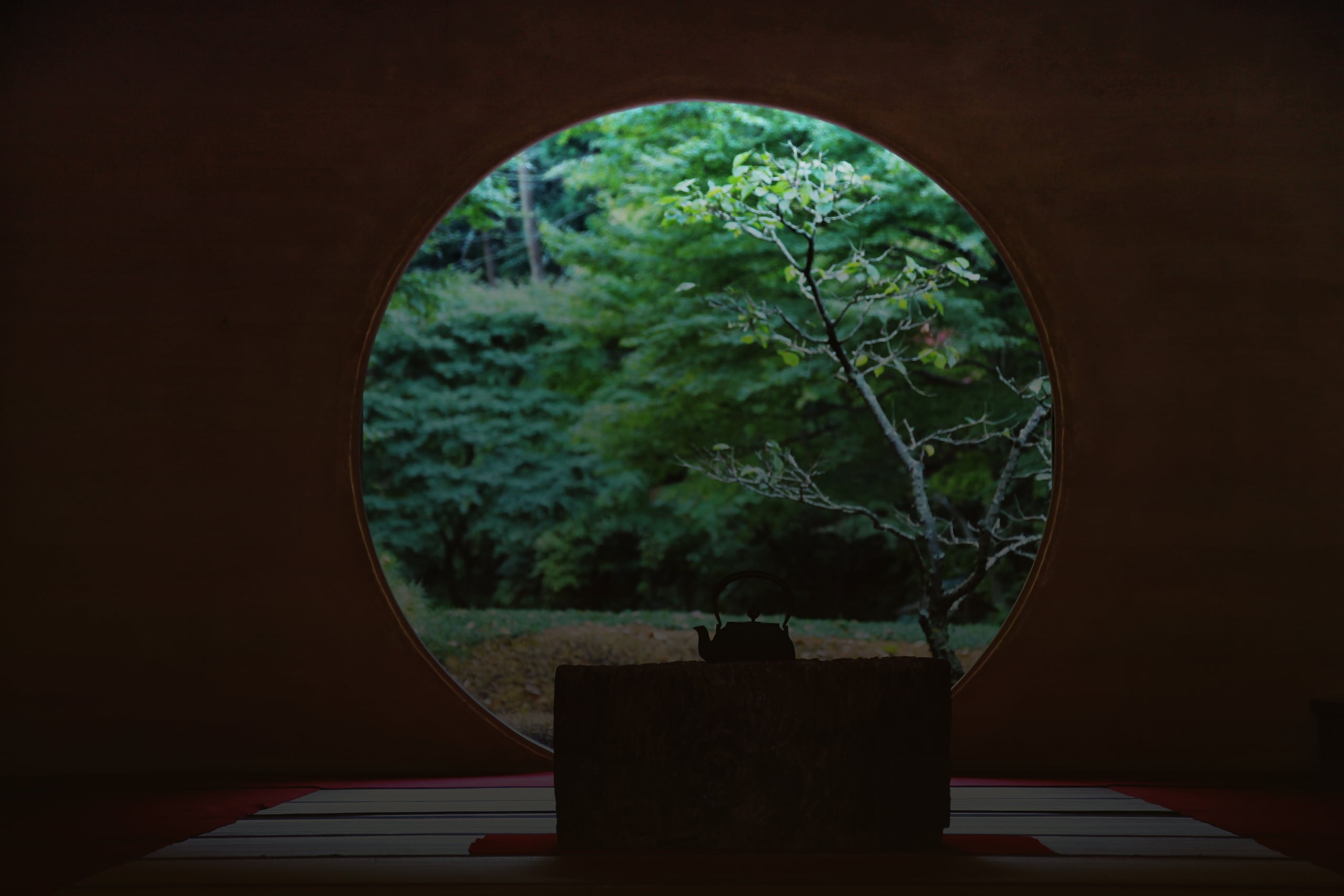 The round window of Meigetsuin framing a green garden beyond a dark tatami room