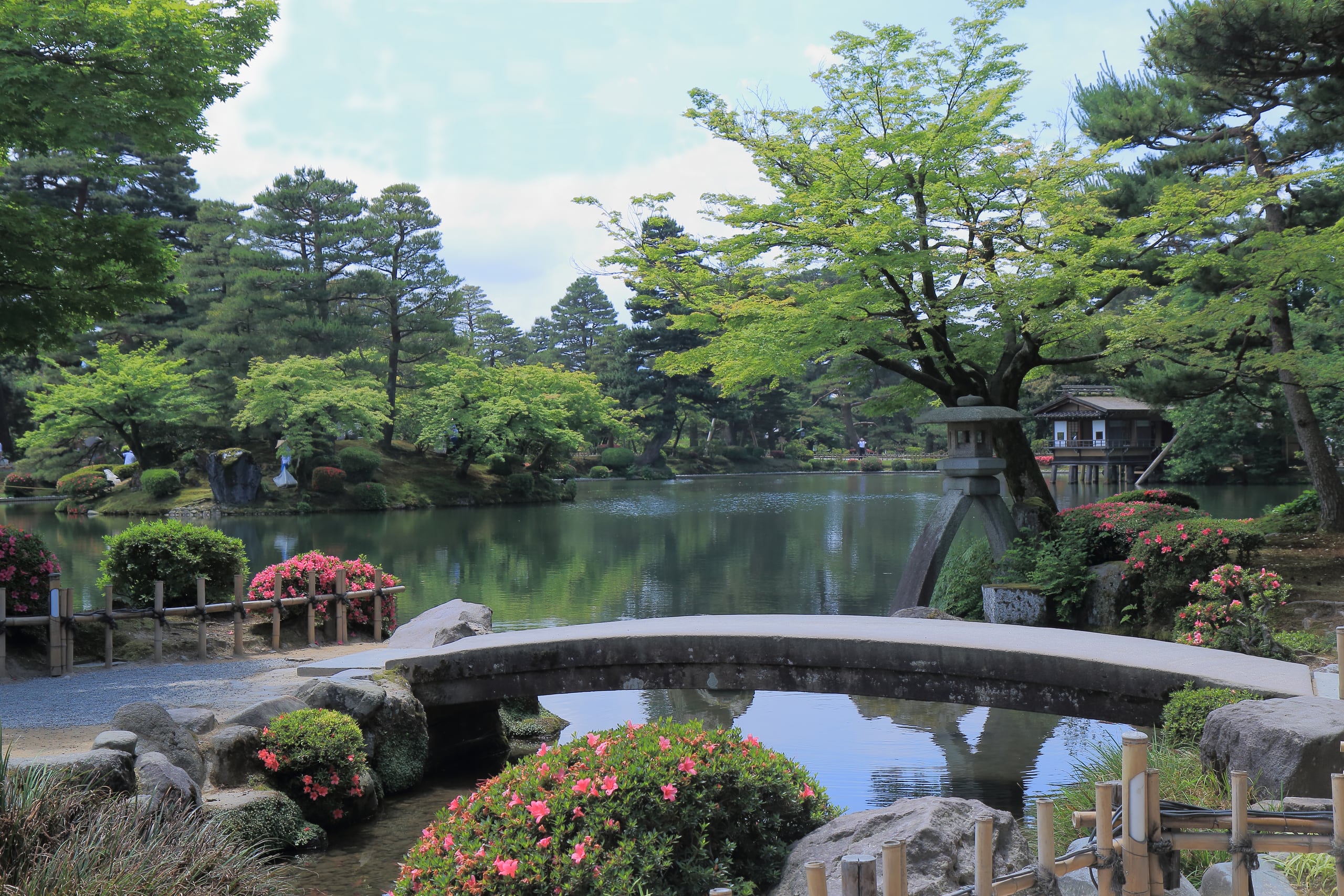 A stone slab bridge over a pond beside the two-legged Kotoji lantern in Kenrokuen garden