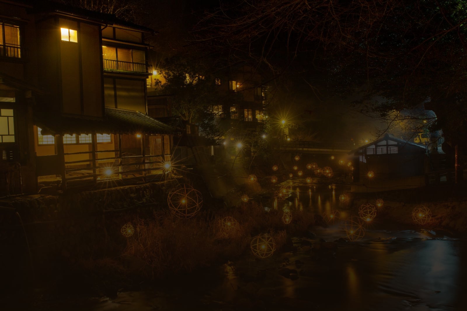 Lit wooden ryokan and lanterns along the canal of Kinosaki Onsen at night