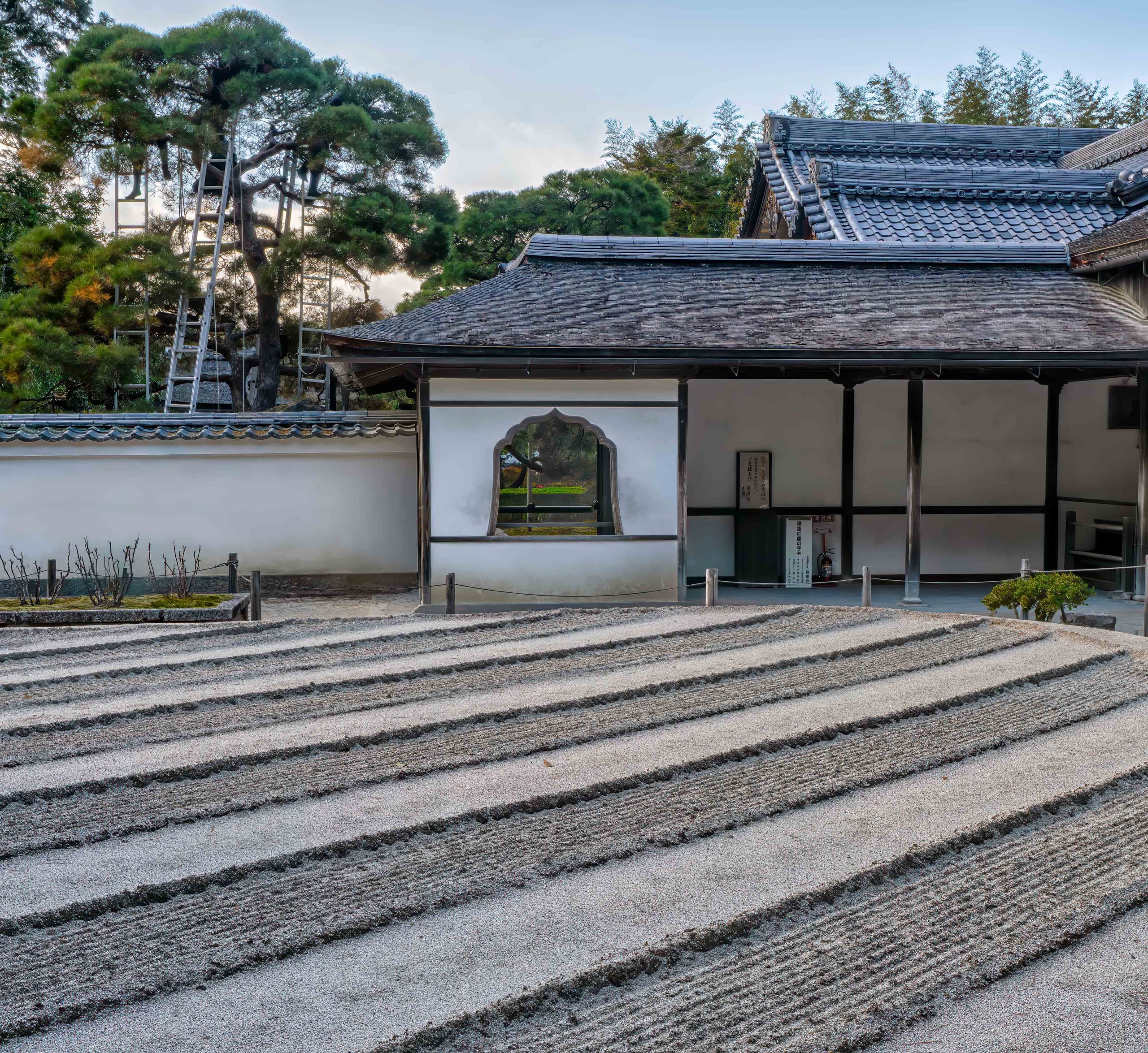 Raked lines of white sand before the plastered walls and tiled roof of a temple hall at Ginkaku-ji