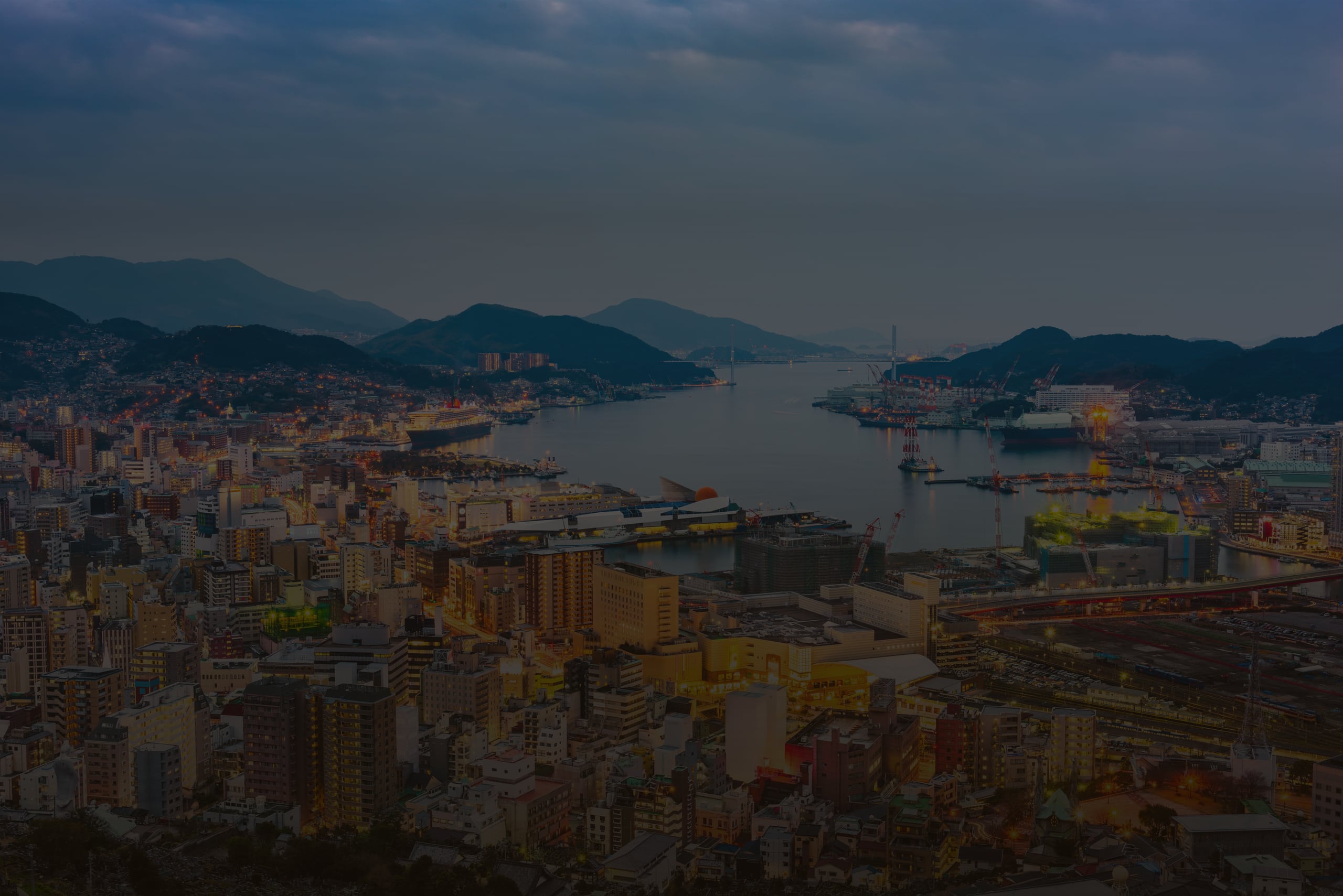 Nagasaki harbour at twilight from Mount Inasa, the city lit along the water and hills beyond