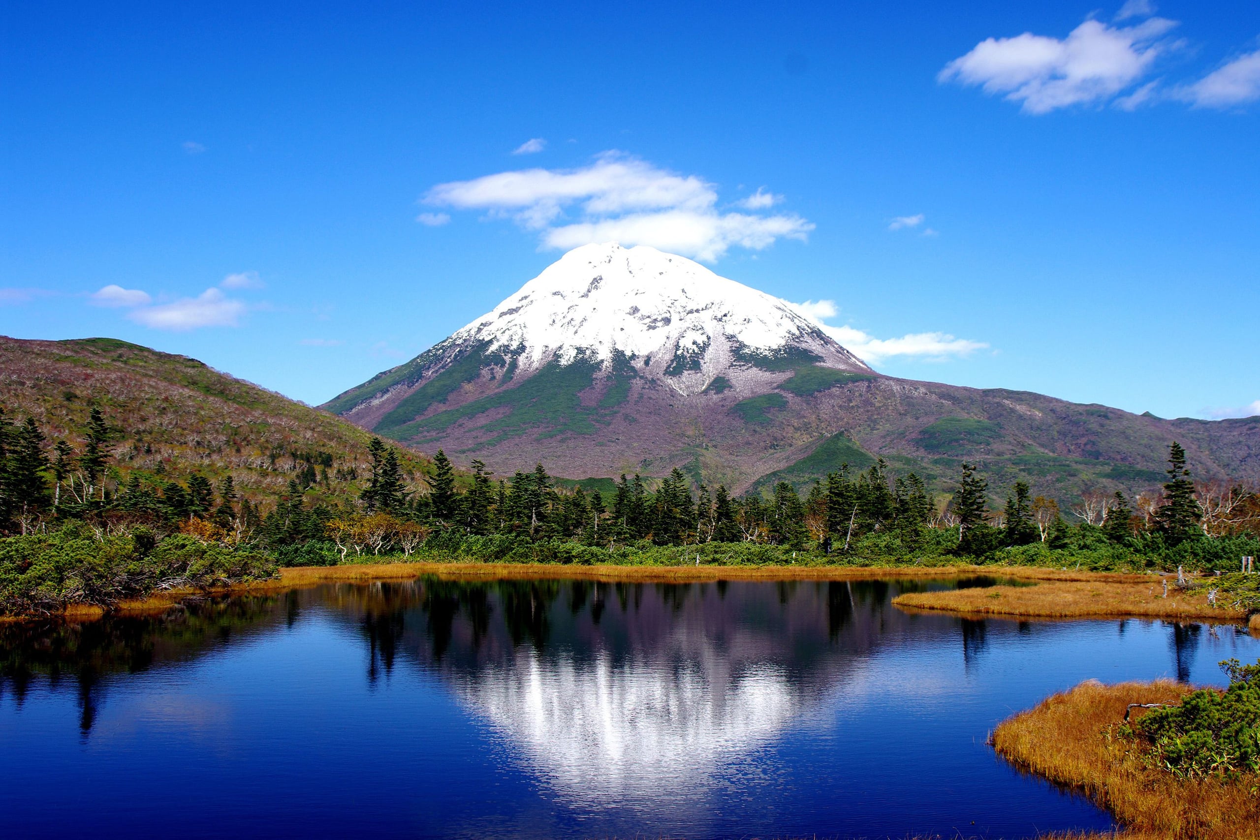 The snow-streaked cone of Mount Rishiri mirrored in the still water of Himenuma, Rishiri Island