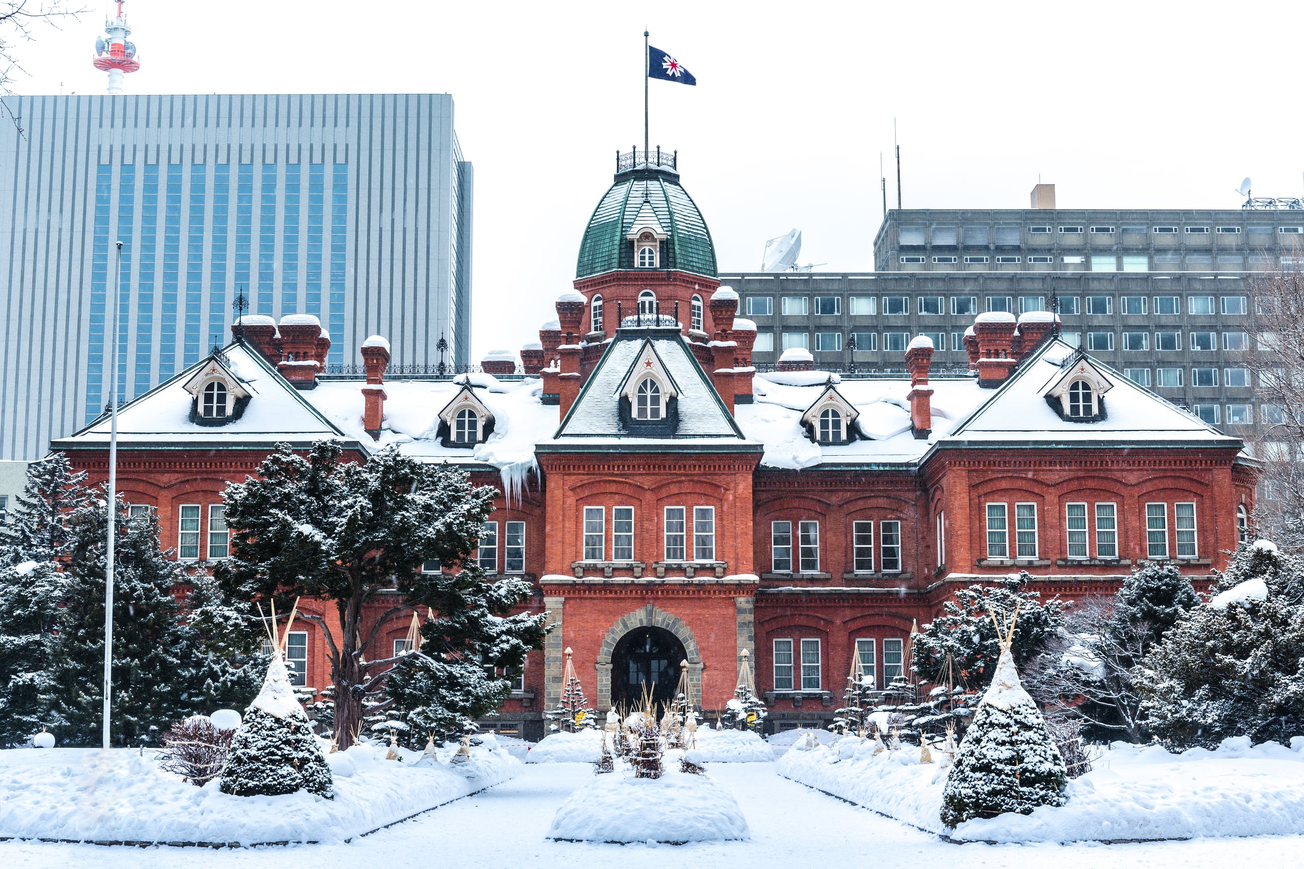 The red-brick former Hokkaido Government Office with its green dome, snow on the trees before it