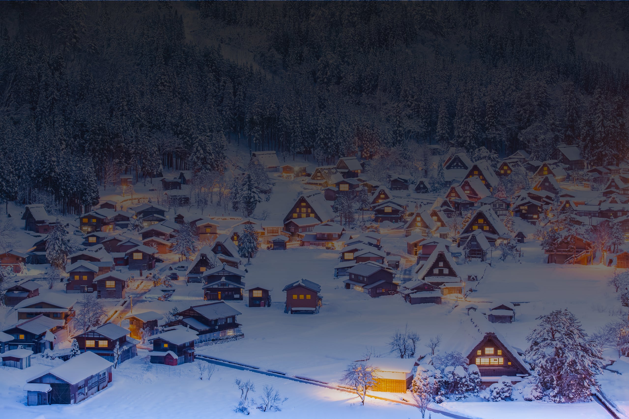 The thatched farmhouses of Ogimachi under snow at night, windows lit, seen from the Shiroyama viewpoint