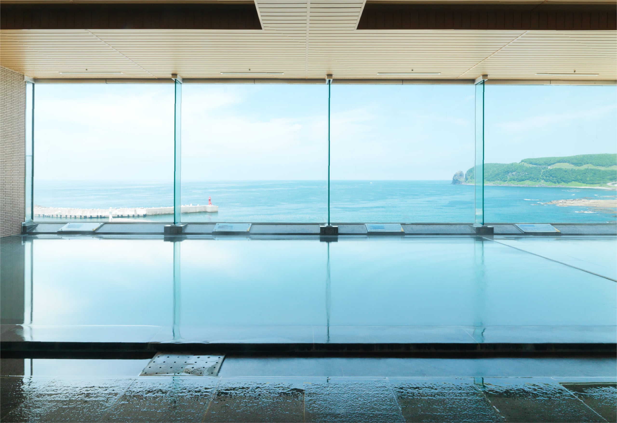 An indoor onsen behind a wall of glass looking over the Okhotsk Sea