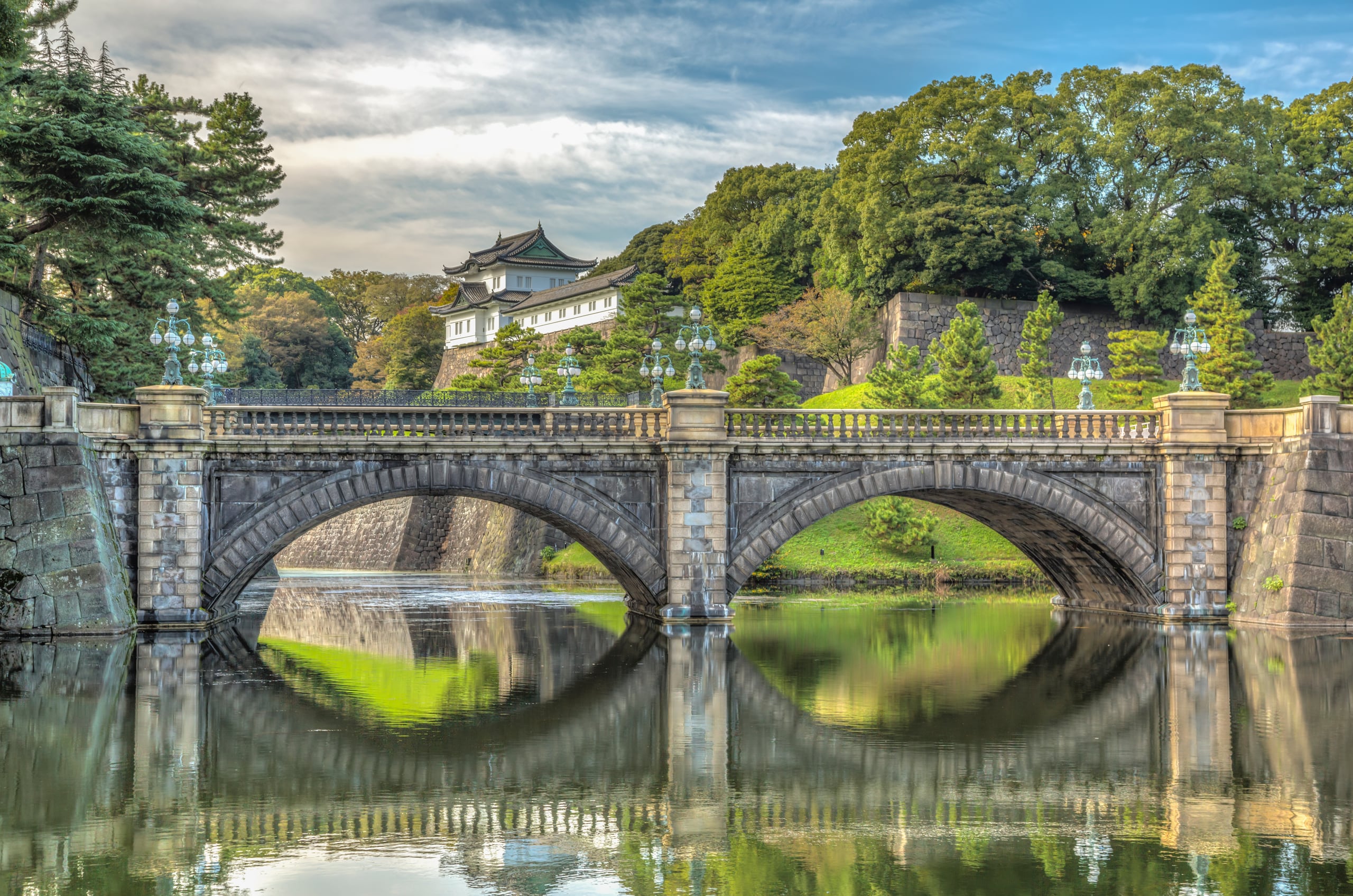 The double-arched stone bridge of Nijubashi reflected in the Imperial Palace moat, a watchtower above