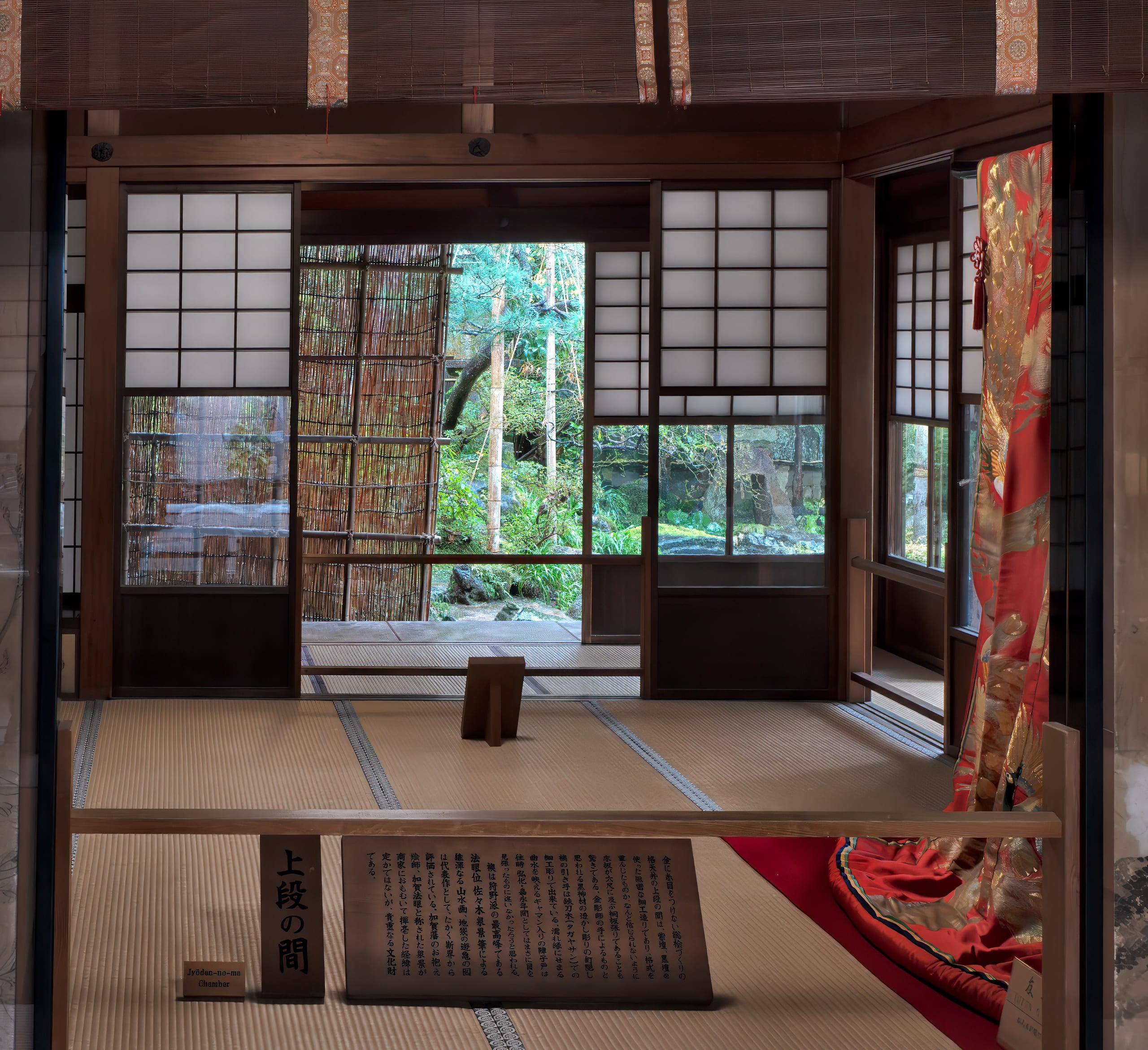 A tatami room in a preserved samurai house in Kanazawa, sliding screens drawn back onto a garden of cedar and moss