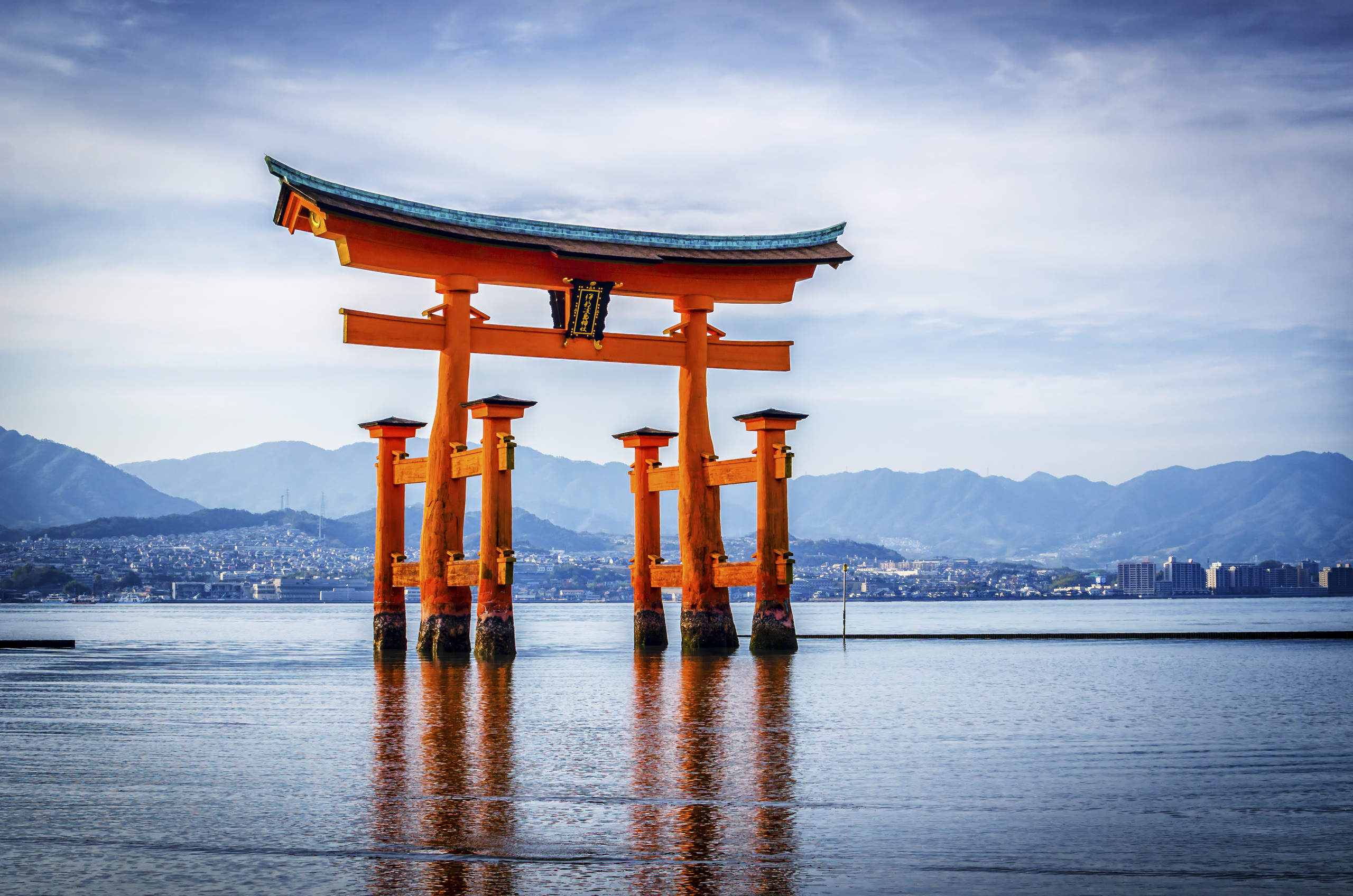 The great torii of Itsukushima Shrine standing in the water off Miyajima, with the mainland across the strait