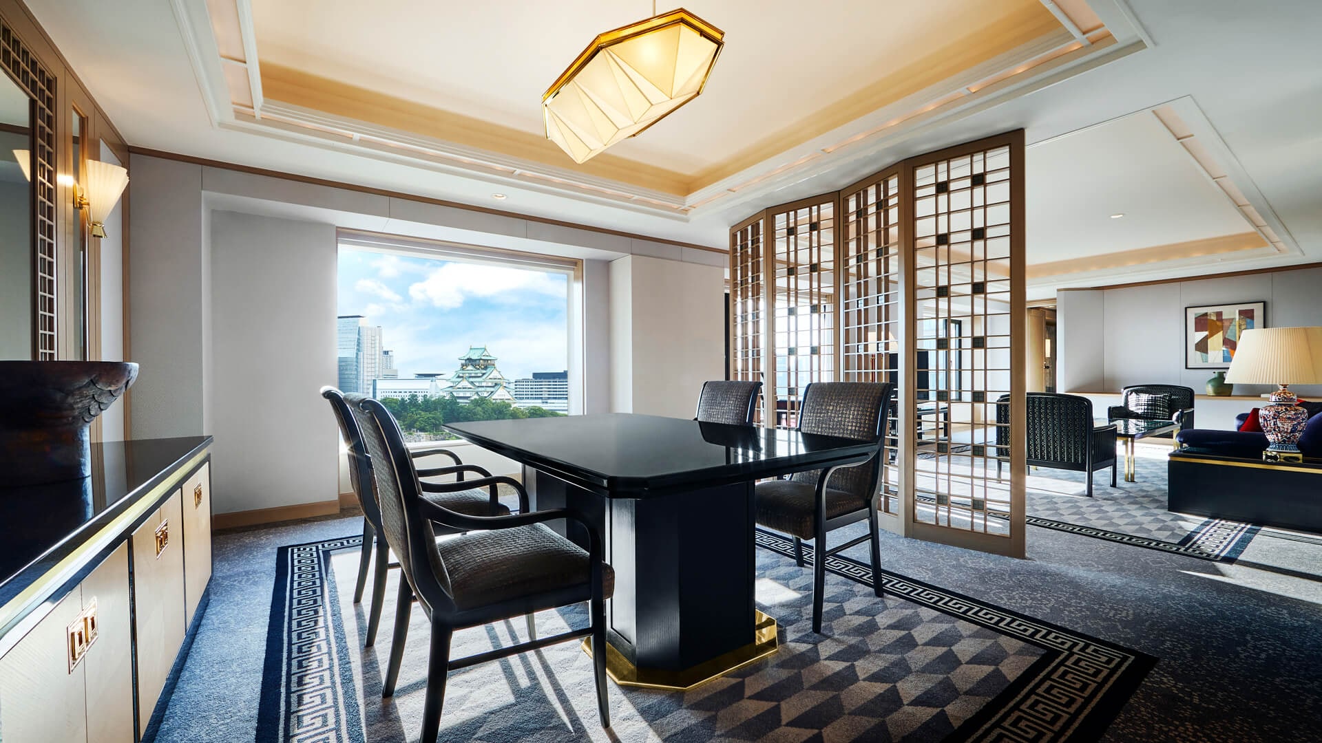 A suite at Hotel New Otani Osaka, a dining table and armchairs before a window onto the trees of the castle park and the keep of Osaka Castle