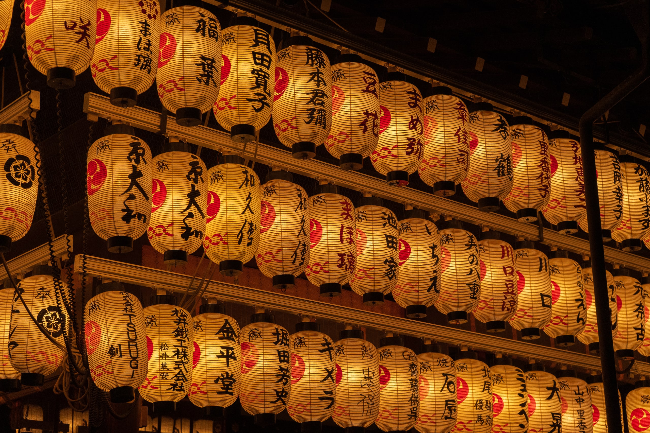 Tiers of white paper lanterns lit in the dance hall of Yasaka Shrine, Gion, each painted with the names of its donors