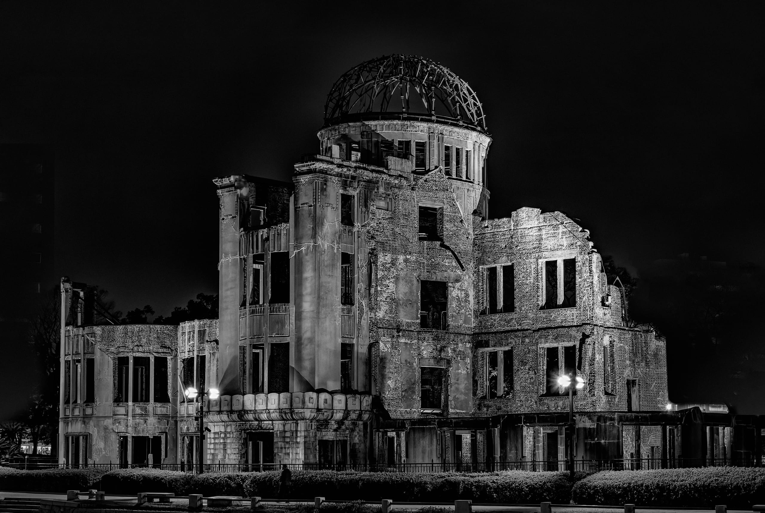 The Atomic Bomb Dome in Hiroshima at night, its ruined frame lit against the dark