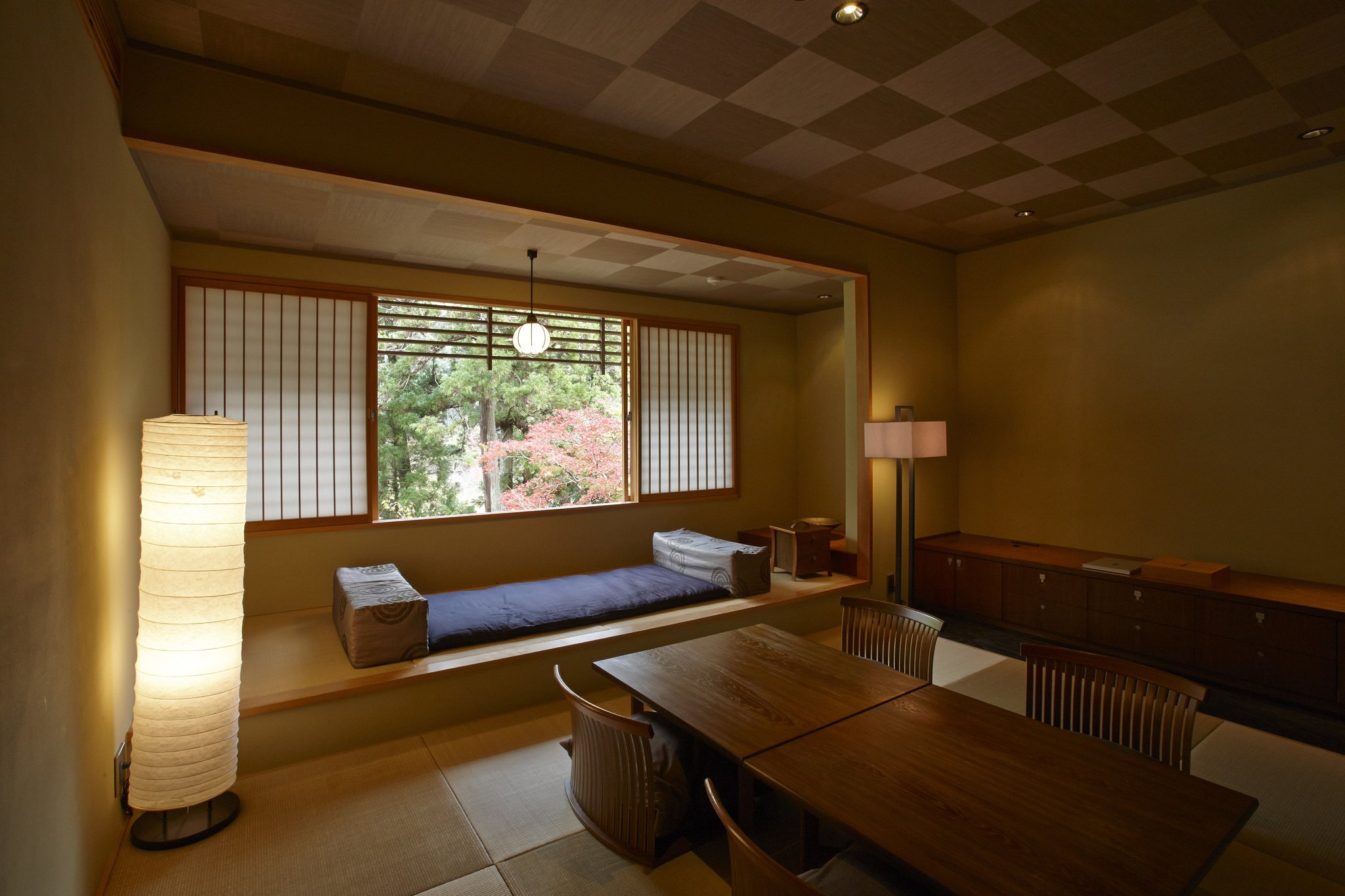 A tatami window seat with a daybed and a paper lantern in a ryokan room