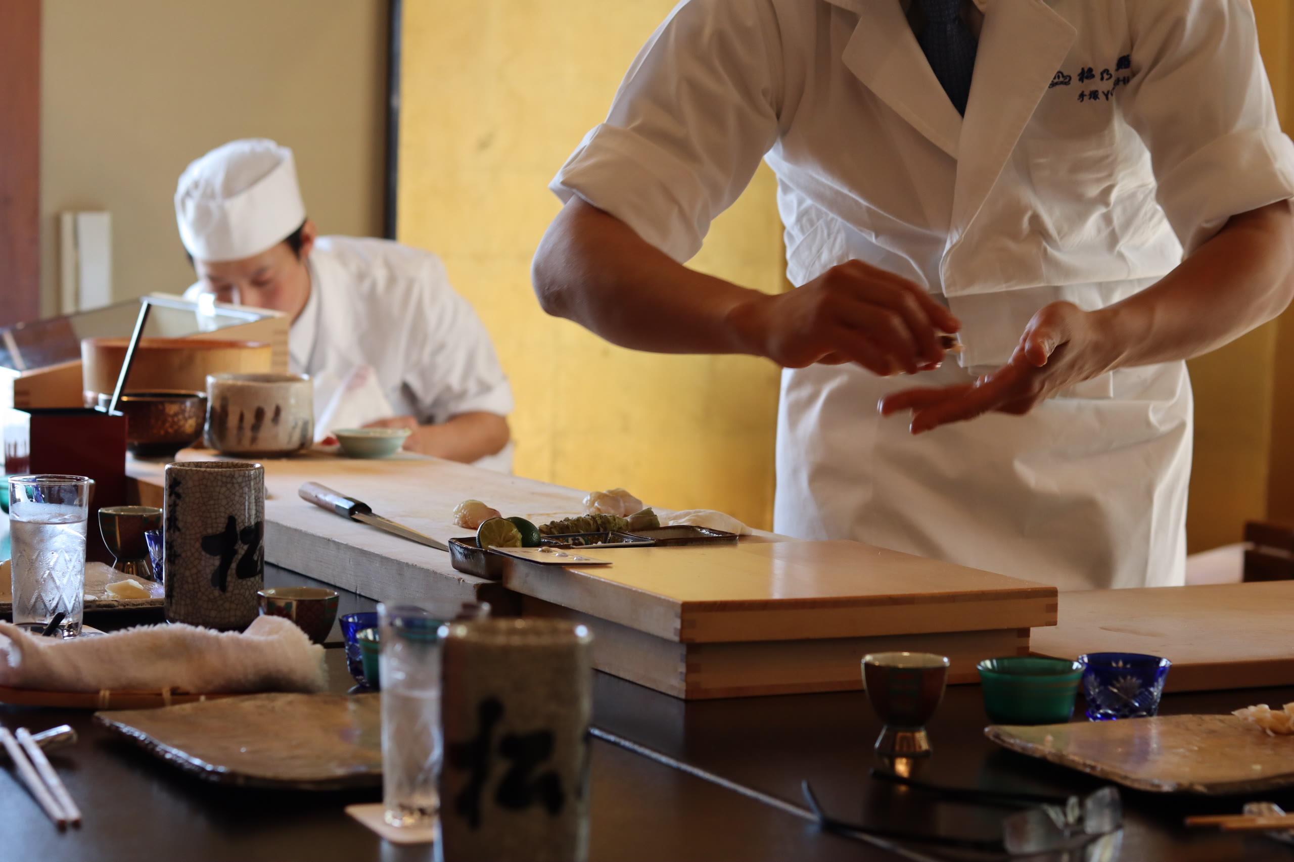 A sushi counter, the chef working through the omakase