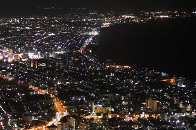 The lights of Hakodate at night, seen from above, the city narrowing between two bays