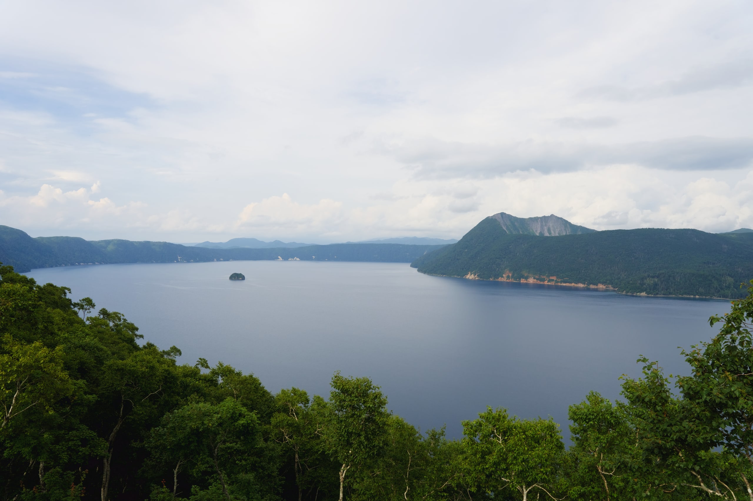 Lake Mashu from the rim in summer, its small island far out on the caldera water