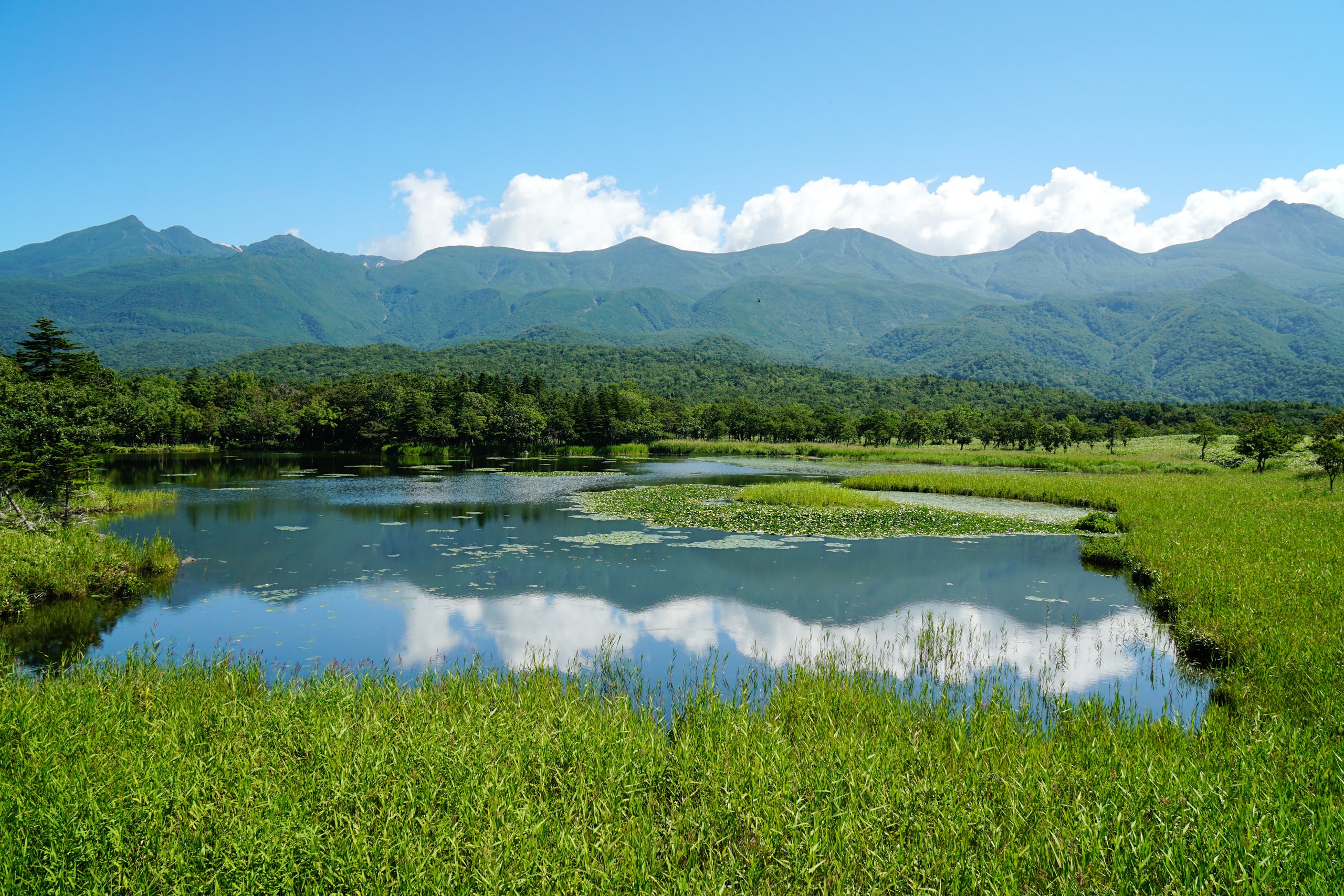 Ichiko, the first of the Shiretoko Five Lakes, mirroring the green range of the peninsula under summer cloud