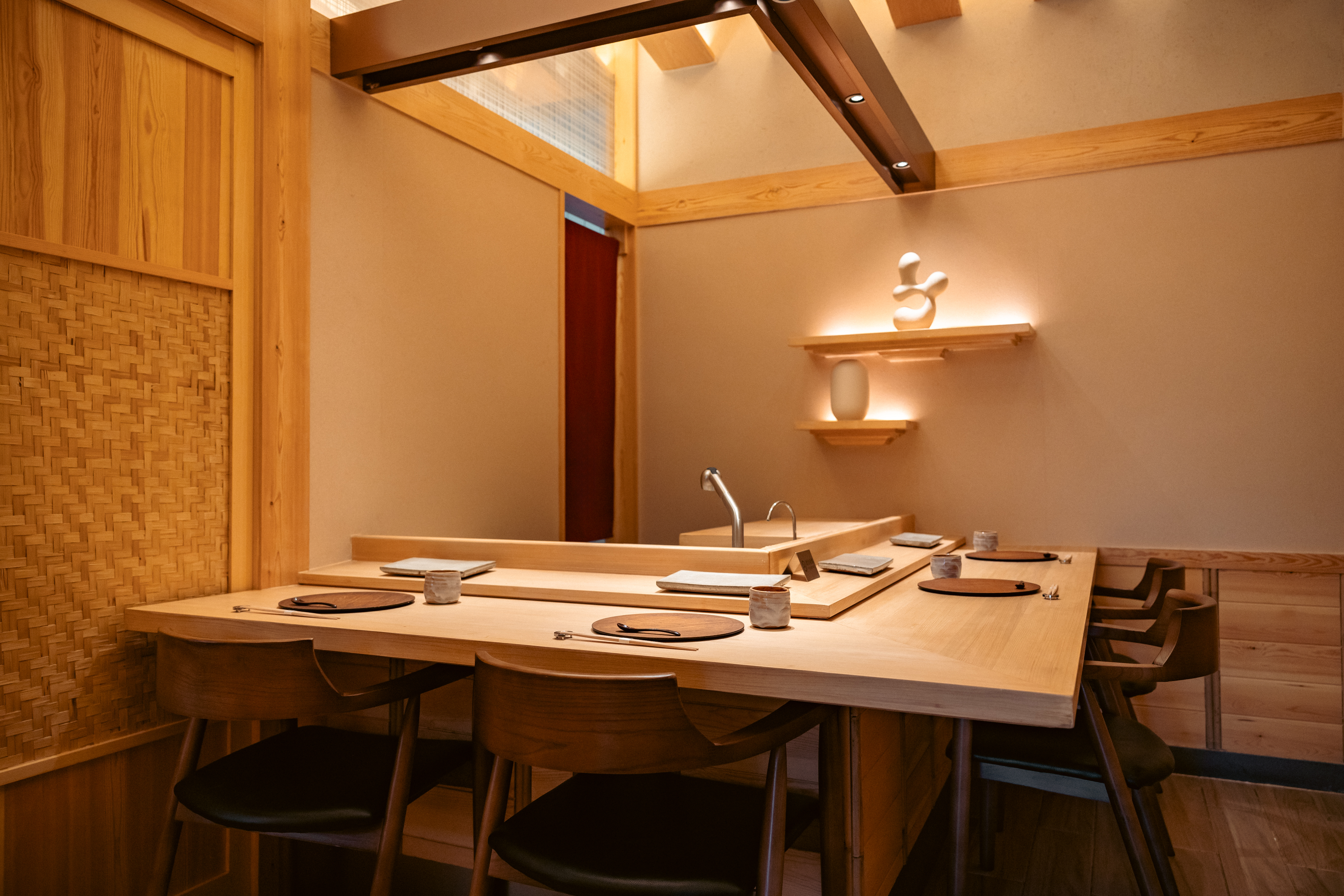 An empty private dining counter in pale wood, set for the meal to come